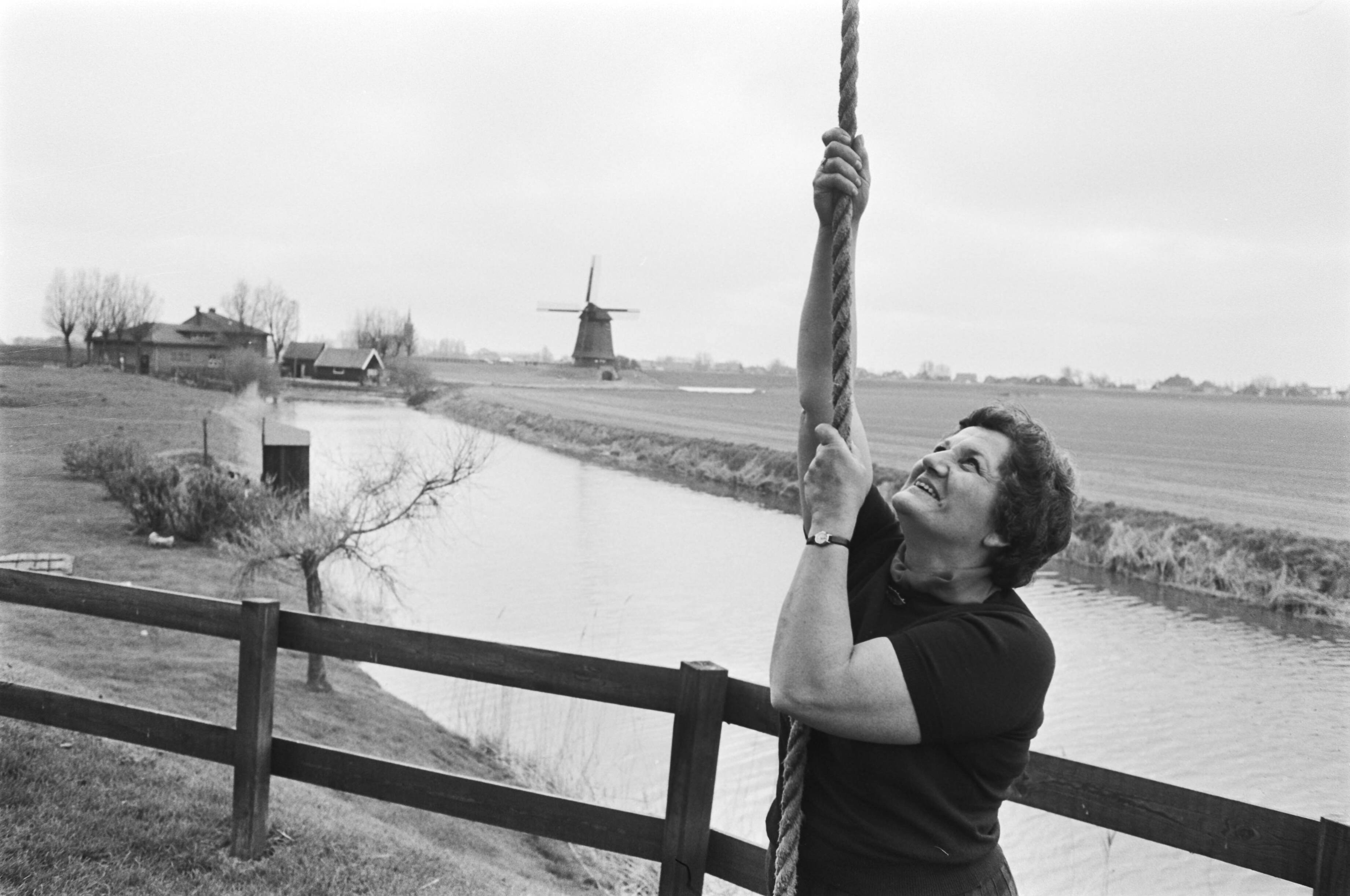 Fotocollectie Anefo — Vrouw in molen te Schermerhorn (Noord-Holland). Vrouw haalt de vang op door middel van het vangtouw en zet de molen in beweging. — Foto: Verhoeff, Bert / Anefo. Licentie: Set B: Rechtenvrij / Publiek Domein. Bron: Nationaal Archief. http://hdl.handle.net/10648/ac81f5f6-d0b4-102d-bcf8-003048976d84