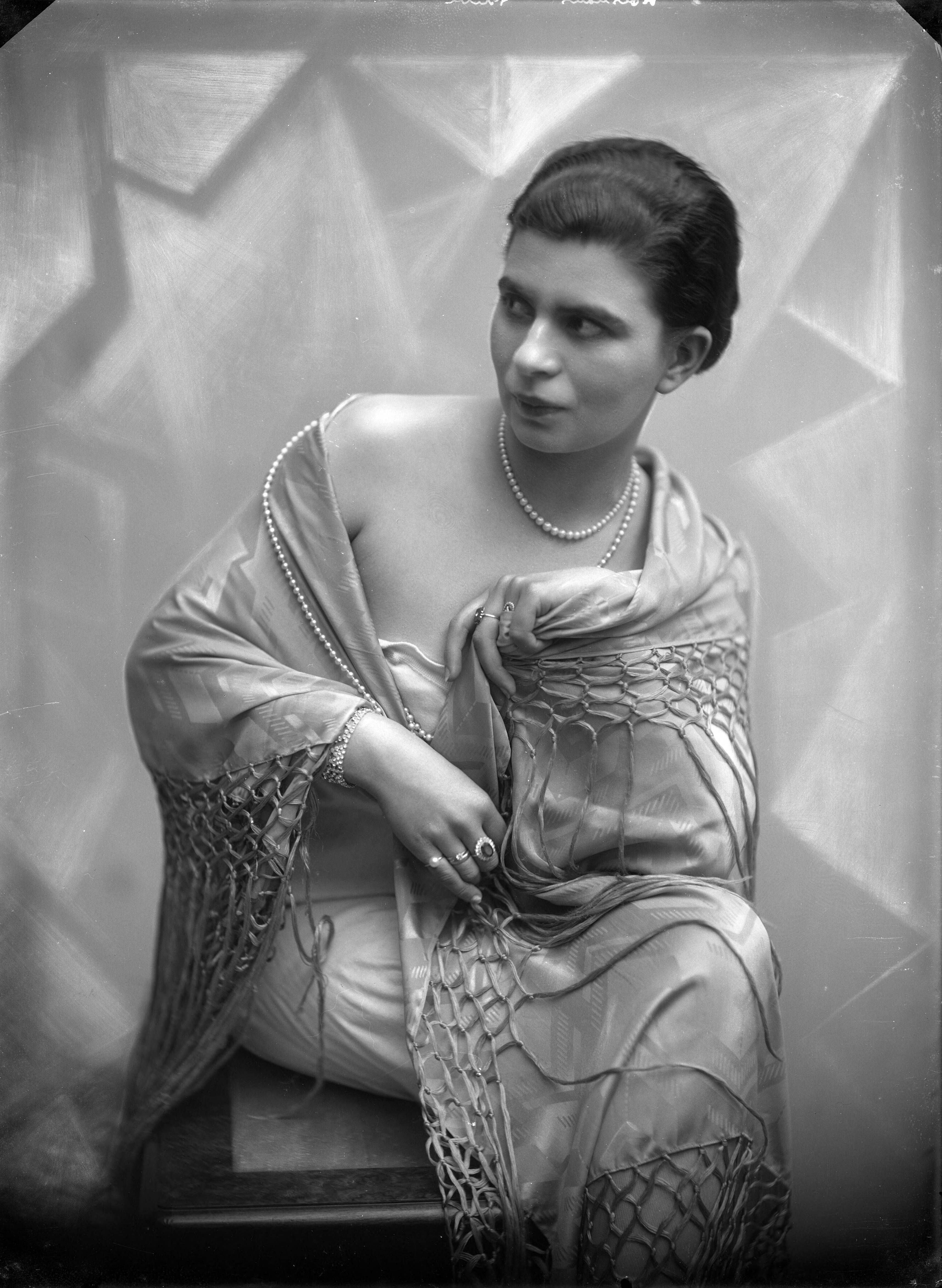 Berg, van den (BERG 050) — Studio-opnames. Een vrouw in een straplessjurk met om haar schouders een grote satijnen shawl met lange franjes gedrapeerd. Holshaus gravure. Haarlem, Nederland 1918-1930. — Foto: Berg, Th.C.J. van den / Spaarnestad Photo (05887). Licentie: Set B: Rechtenvrij / Publiek Domein. Bron: Nationaal Archief. http://hdl.handle.net/10648/35429da7-c559-a382-e063-6df0900a6686