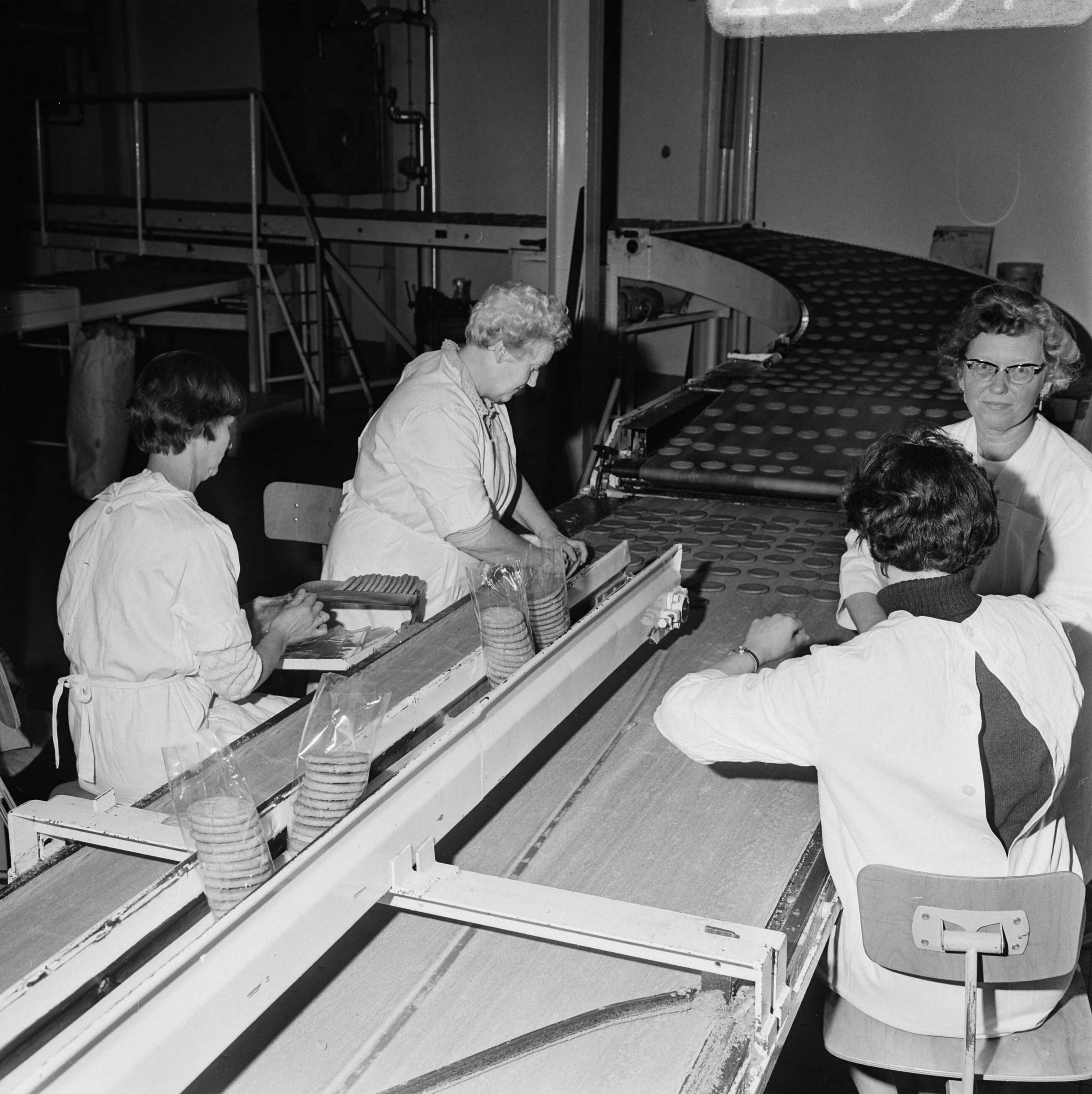 Fotocollectie Anefo — Opdracht Elsevier getrouwde vrouwen aan het werk aan lopende band bij Albert Heyn (Zaandam) — Foto: Mieremet, Rob / Anefo. Licentie: Set B: Rechtenvrij / Publiek Domein. Bron: Nationaal Archief. http://hdl.handle.net/10648/ab622f4c-d0b4-102d-bcf8-003048976d84