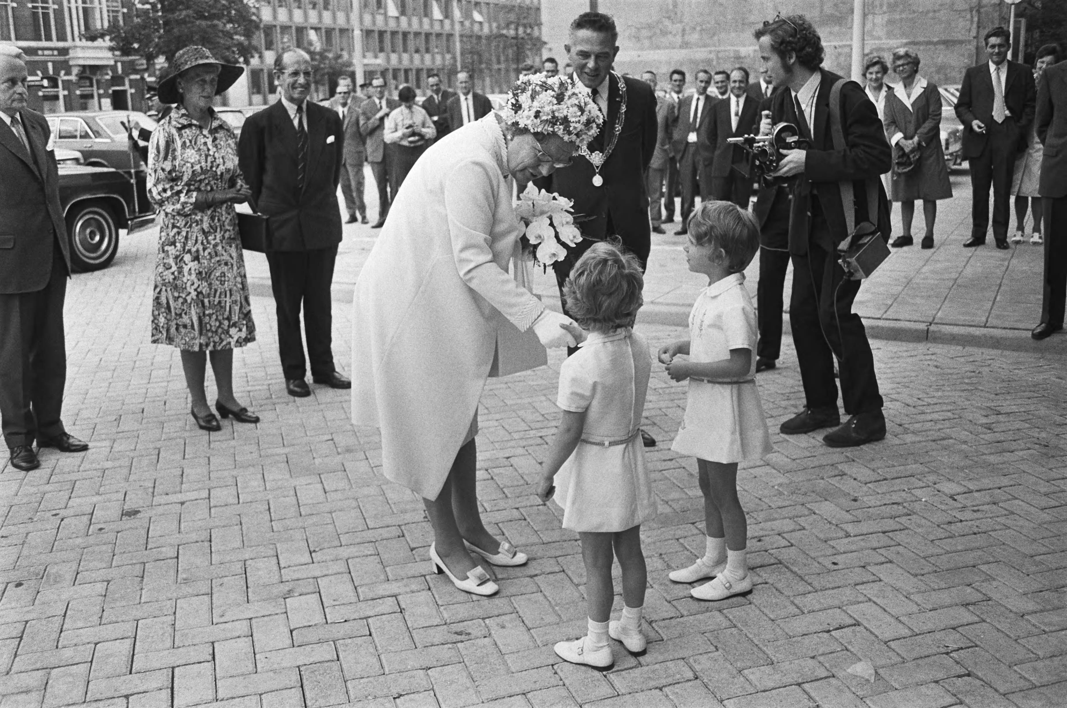 Koningin Juliana opent nieuwe SER gebouw Den Haag — Koningin Juliana krijgt bij haar aankomst bij het SER-gebouw bloemen aangeboden; rechts, met ambtsketen, burgemeester Marijnen van Den Haag — Foto: Fotograaf Onbekend / Anefo. Licentie: Set B: Rechtenvrij / Publiek Domein. Bron: Nationaal Archief. http://hdl.handle.net/10648/abc507b6-d0b4-102d-bcf8-003048976d84