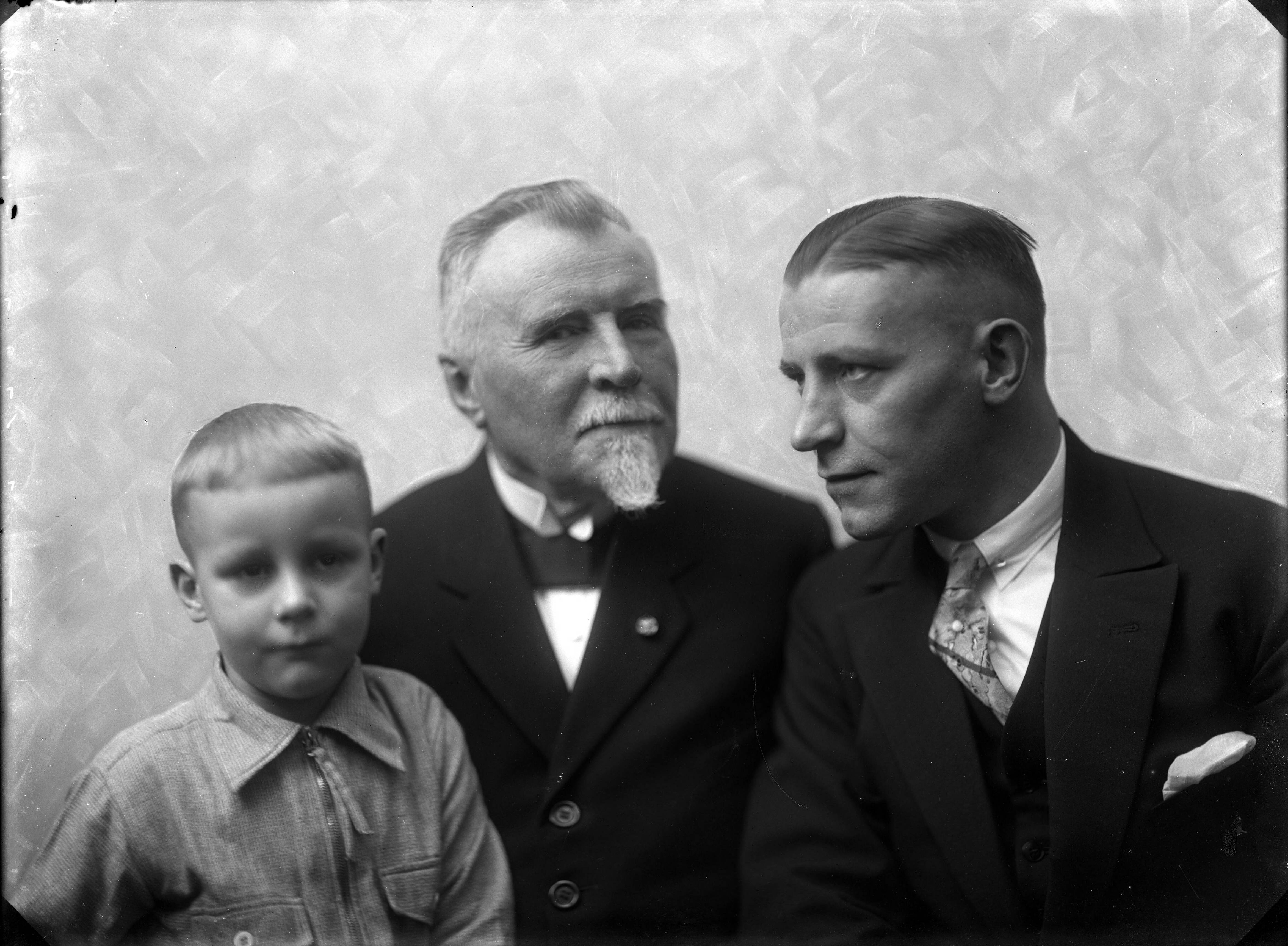 Portretten — Studio-opname, portret van drie generaties tezamen. Opa met sik, vader met opgeschoren kapsel in de pommade en jongetje met blouse en kort ponykapsel. Haarlem, Nederland, 1918-1930. 9655 Schuilenburg gravure — Foto: Berg, Th.C.J. van den / Spaarnestad Photo (05887). Licentie: Set B: Rechtenvrij / Publiek Domein. Bron: Nationaal Archief. http://hdl.handle.net/10648/35429da7-c70a-a382-e063-6df0900a6686