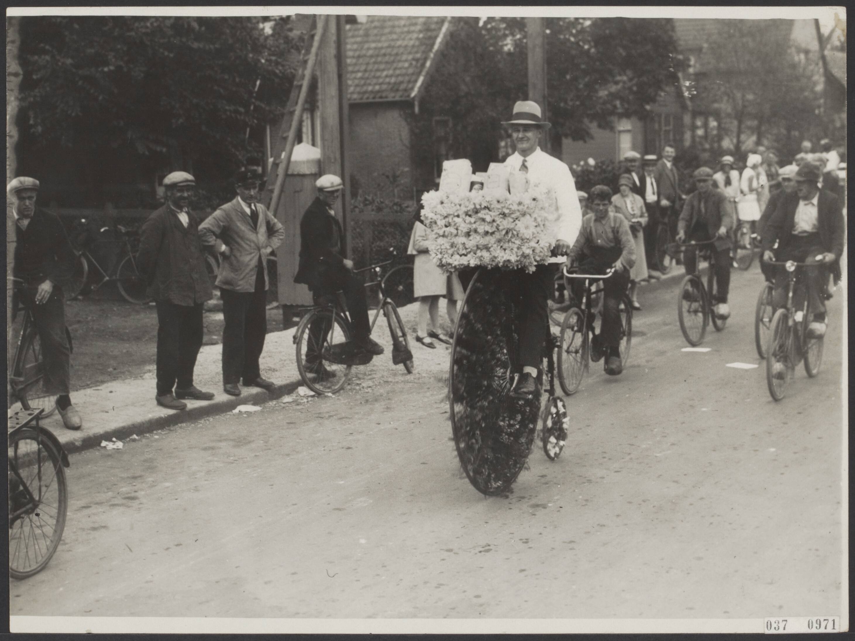 Fotocollectie Elsevier Binnenland — Bloemencorso Aalsmeer. Man op versierde velocipede aan het Oosteinde — Foto: Vogt & Peets (Internationaal Illustratiebureau). Licentie: Set B: Rechtenvrij / Publiek Domein. Bron: Nationaal Archief. http://hdl.handle.net/10648/adef7bac-d0b4-102d-bcf8-003048976d84