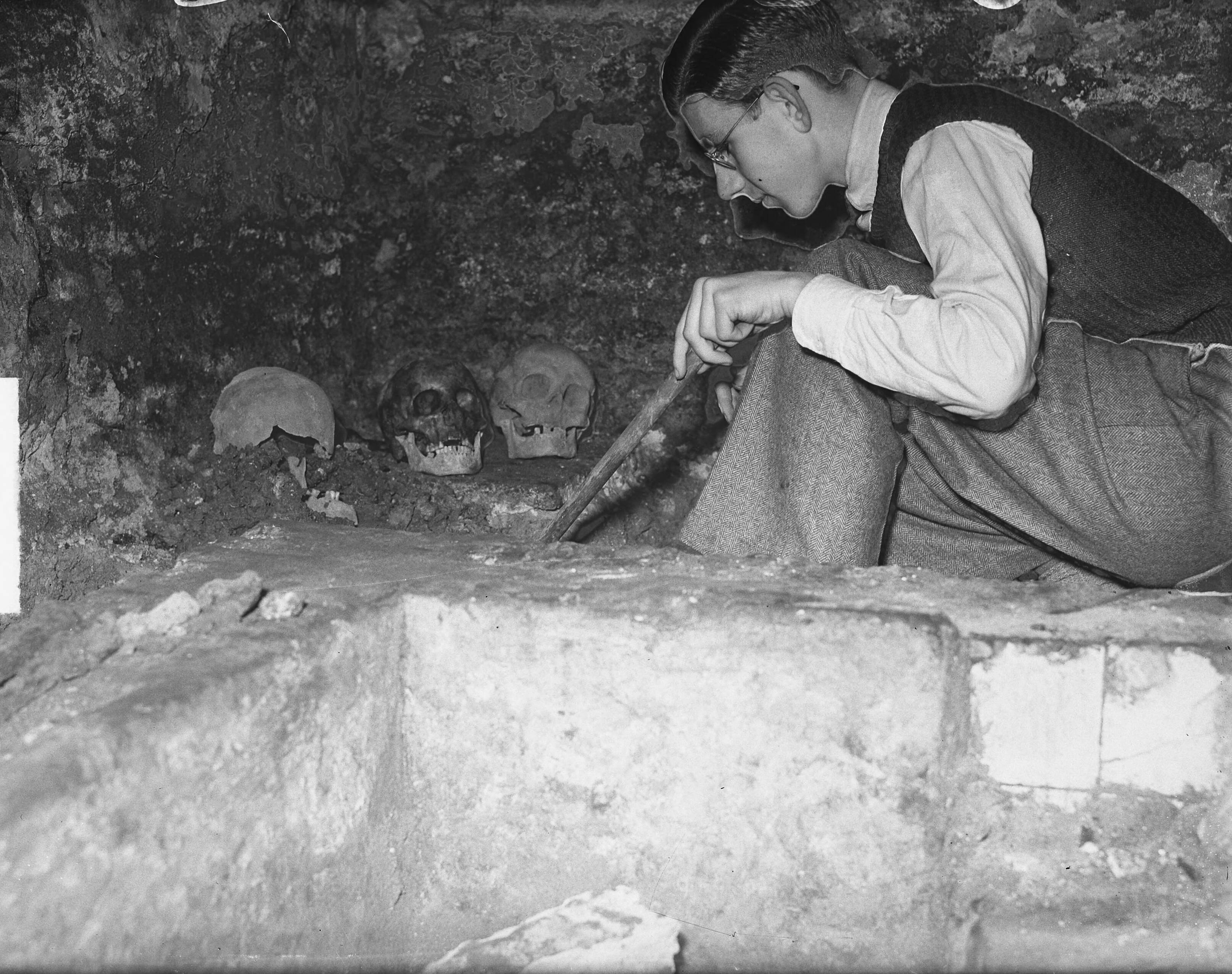 Fotocollectie Anefo — Haarlemse scholier genaam Frans Damen verricht opgravingen onder de drukkerij van zijn vader in de Spaarnwouderstraat, waar volgens de geschiedenisles op school een Augustijnerkapel uit de 15de eeuw moet hebben gestaan. De jeugdige oudheidkundige bij het stuk muurr dat hij aan de oppervlaket heeft gebracht, terwijl ook enige doodskoppen werden opgegraven. Sedert 5 januari j.l. graaft Frans Damen — Foto: Oorschot, […] van / Anefo. Licentie: Set B: Rechtenvrij / Publiek Domein. Bron: Nationaal Archief. http://hdl.handle.net/10648/a8e624ee-d0b4-102d-bcf8-003048976d84