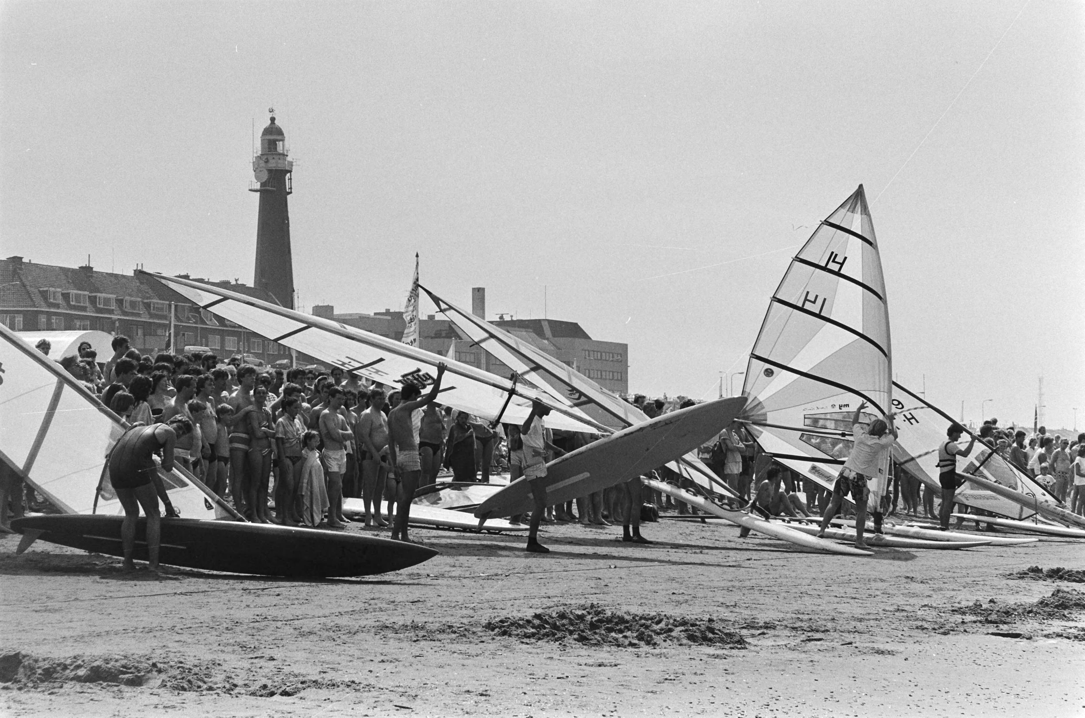 Fotocollectie Anefo — Wedstrijd in Scheveningen om Holland Surf Cup ; de surfers aan de start, er achter het publiek — Foto: Vollebregt, Sjakkelien / Anefo. Licentie: Set B: Rechtenvrij / Publiek Domein. Bron: Nationaal Archief. http://hdl.handle.net/10648/ad470490-d0b4-102d-bcf8-003048976d84