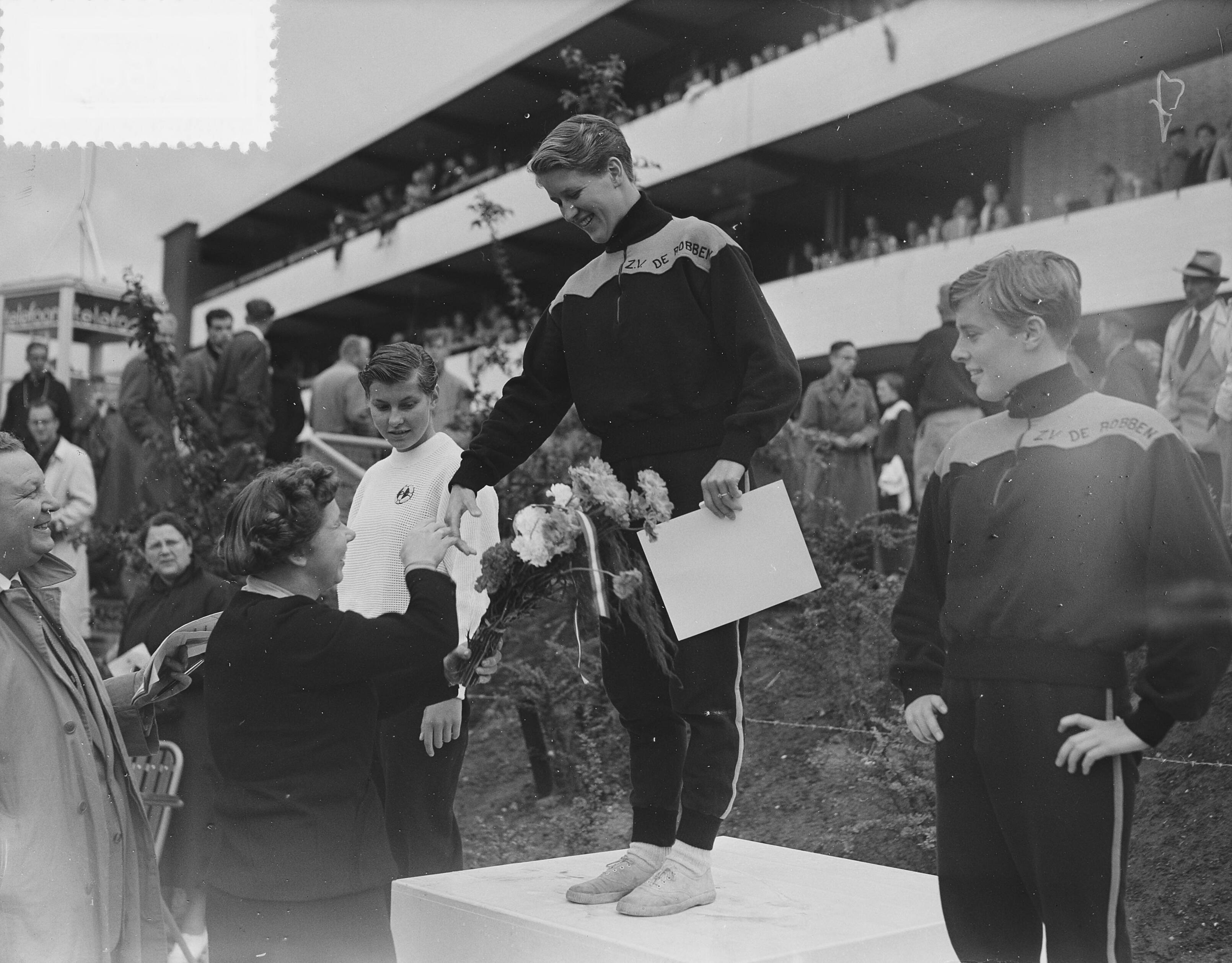 Fotocollectie Anefo — Nederlandse kampioenschappen zwemmen te Groningen, Huldiging 1500 meter vrije slag dames. Winnares Lenie de Nijs wordt gefelicteerd. Links van haar Jopie van Alphen (2e) en rechts Mary Kok (3e) — Foto: Bilsen, Joop van / Anefo. Licentie: Set B: Rechtenvrij / Publiek Domein. Bron: Nationaal Archief. http://hdl.handle.net/10648/a9393bca-d0b4-102d-bcf8-003048976d84
