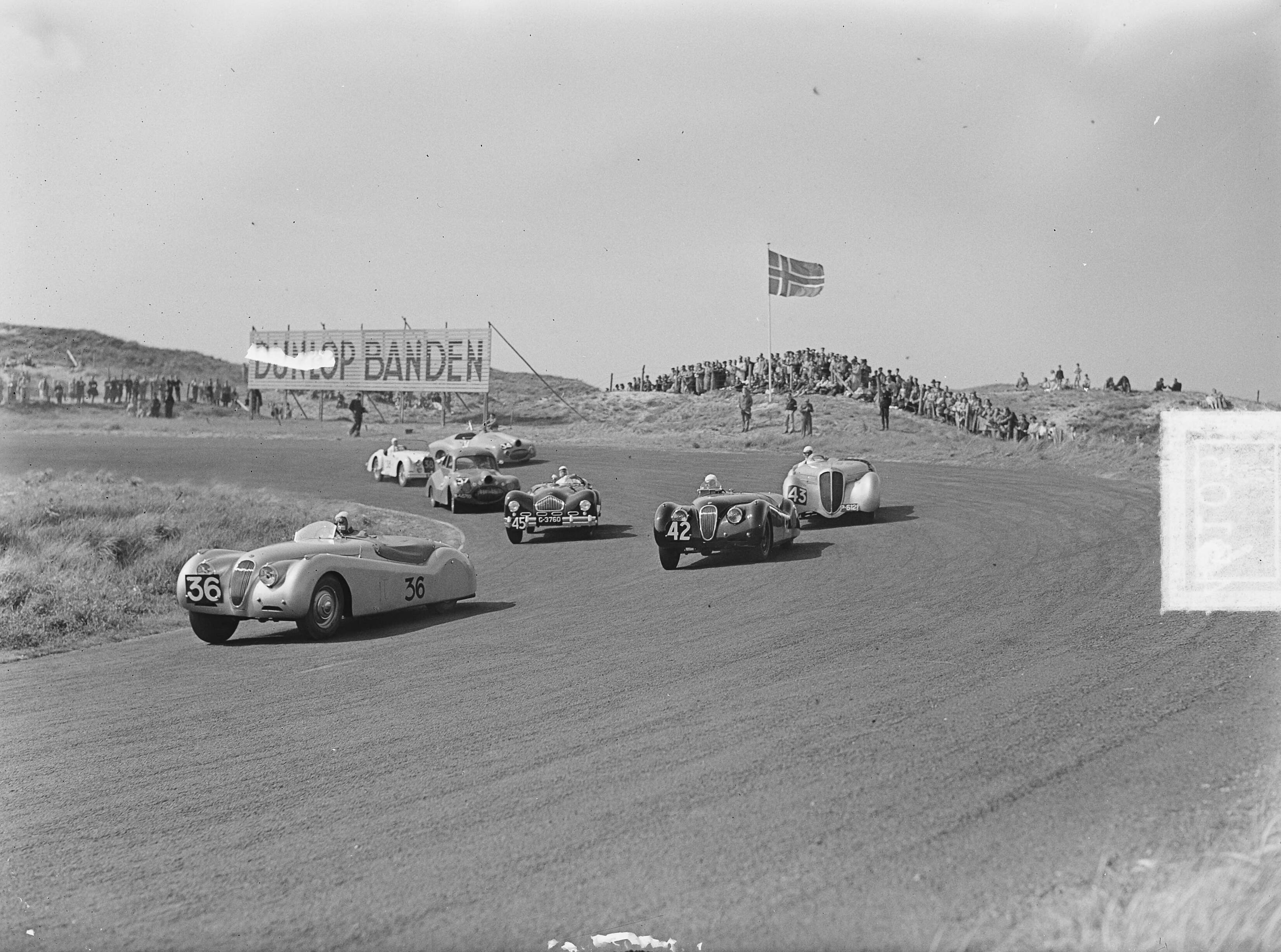 Motor- en autoraces KNAC en KNMV op het circuit van Zandvoort — Motor- en autoraces van KNAC en KNMV op het circuit van Zandvoort [klasse boven 2000cc in de Tarzanbocht. Voorop winnaar dr. Oei Tjong Bo met zijn Jaguar (nr. 36). Daarachter met nr. 42 Van Dieten, ook met een Jaguar en no 43, Tielens met een Delahaye] — Foto: Pot, Harry / Anefo. Licentie: Set B: Rechtenvrij / Publiek Domein. Bron: Nationaal Archief. http://hdl.handle.net/10648/a8eb4b18-d0b4-102d-bcf8-003048976d84