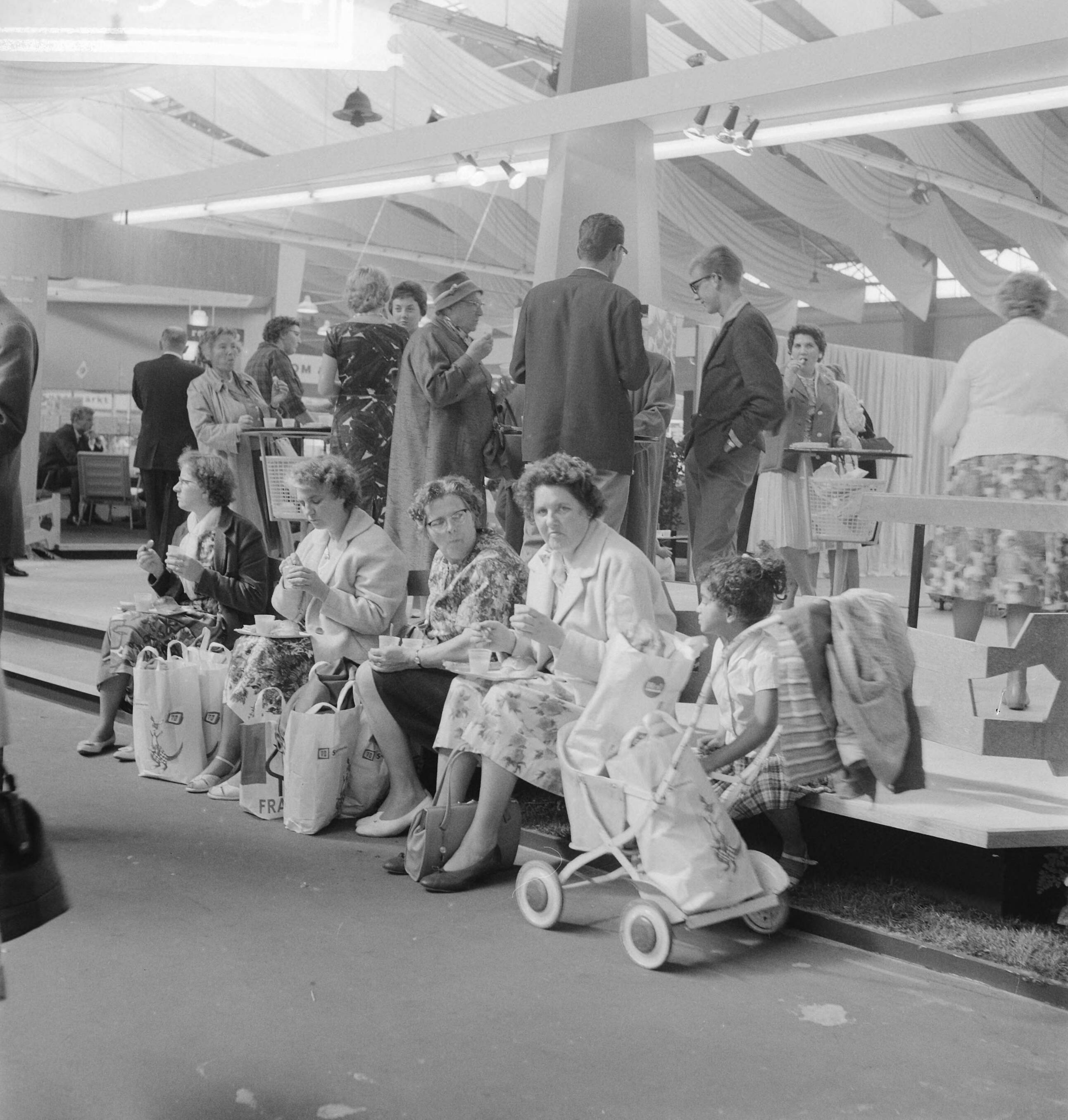 Fotocollectie Anefo — Opening internationale tentoonstelling "Spijs en Drank" in de Houtrusthallen te Den Haag. Etende bezoekers — Foto: Koch, Eric / Anefo. Licentie: Set B: Rechtenvrij / Publiek Domein. Bron: Nationaal Archief. http://hdl.handle.net/10648/a9e1b598-d0b4-102d-bcf8-003048976d84