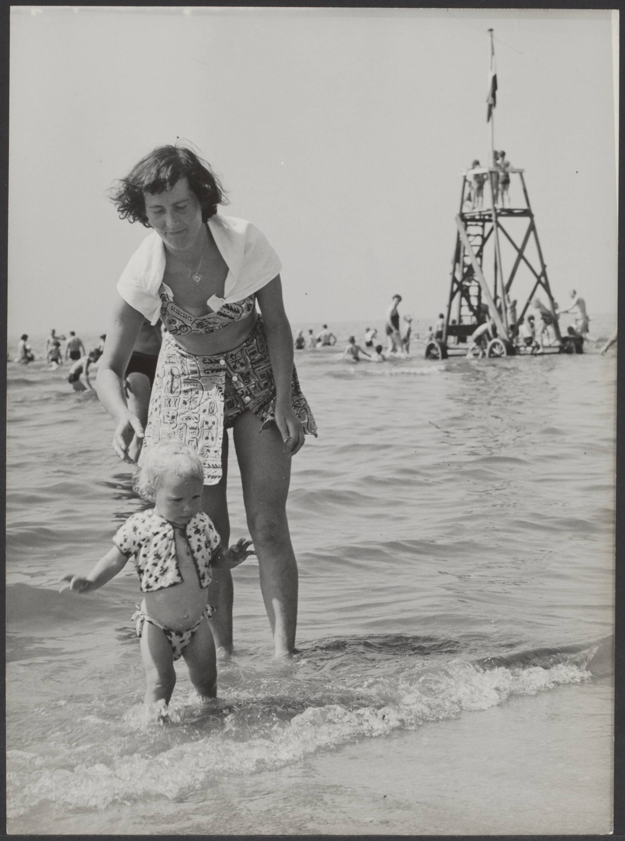 Fotocollectie Elsevier Binnenland — [Strandleven. Een peuter waagt zich in zee onder toezicht van de moeder] — Foto: Fotograaf Onbekend / Anefo. Licentie: Set B: Rechtenvrij / Publiek Domein. Bron: Nationaal Archief. http://hdl.handle.net/10648/adf8d828-d0b4-102d-bcf8-003048976d84