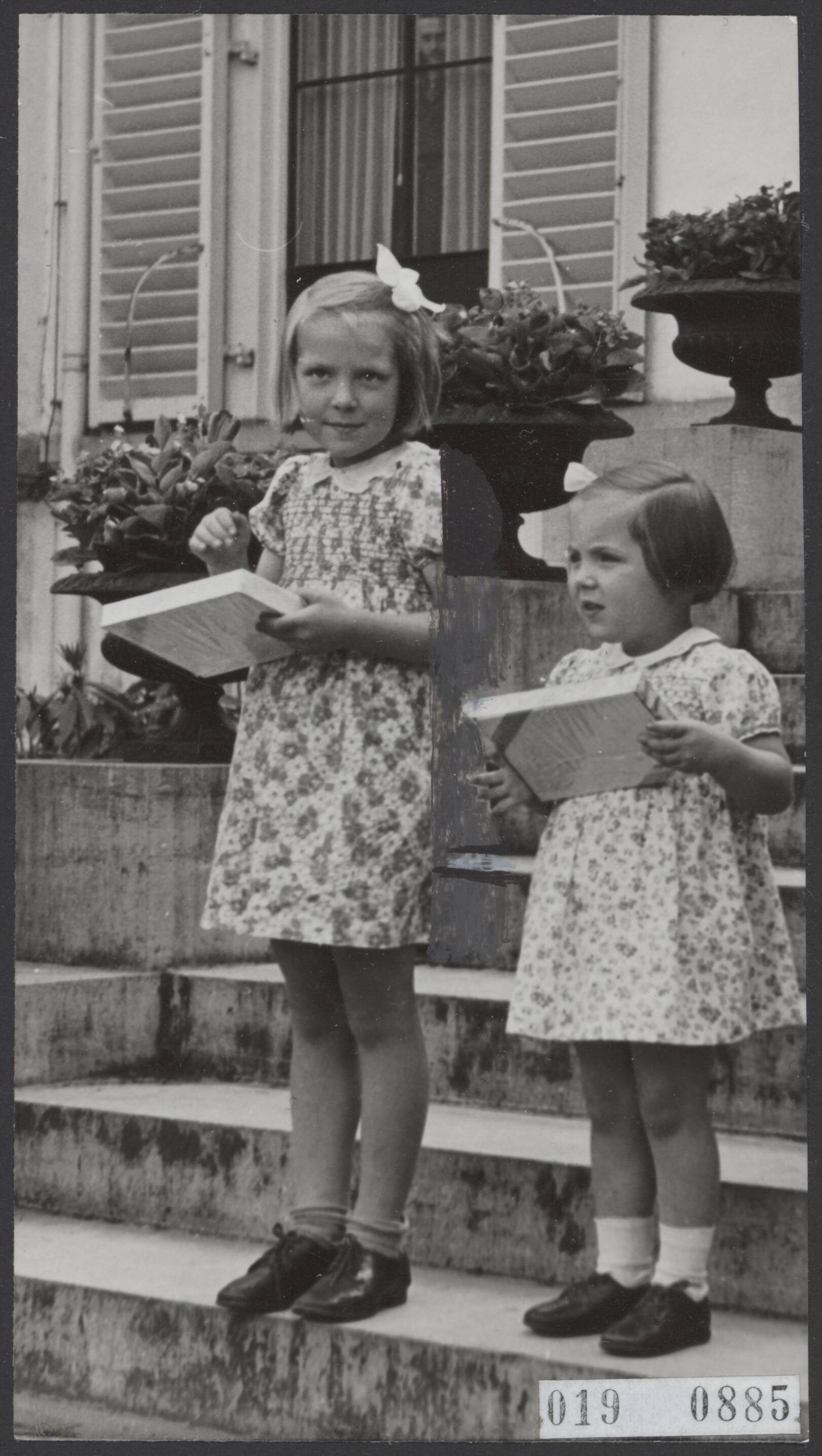 Fotocollectie Elsevier Binnenland — [Prinses Irene en prinses Margriet, ieder met een doos in de hand op de trappen van het paleis Soestdijk, tijdens een bezoek van 260 bejaarden uit Nijkerk op den jaarlijkse tocht van het Nijkerkse Comité Zonnedag — Foto: Fotopersbureau "Holland". Licentie: Set B: Rechtenvrij / Publiek Domein. Bron: Nationaal Archief. http://hdl.handle.net/10648/adc7f712-d0b4-102d-bcf8-003048976d84