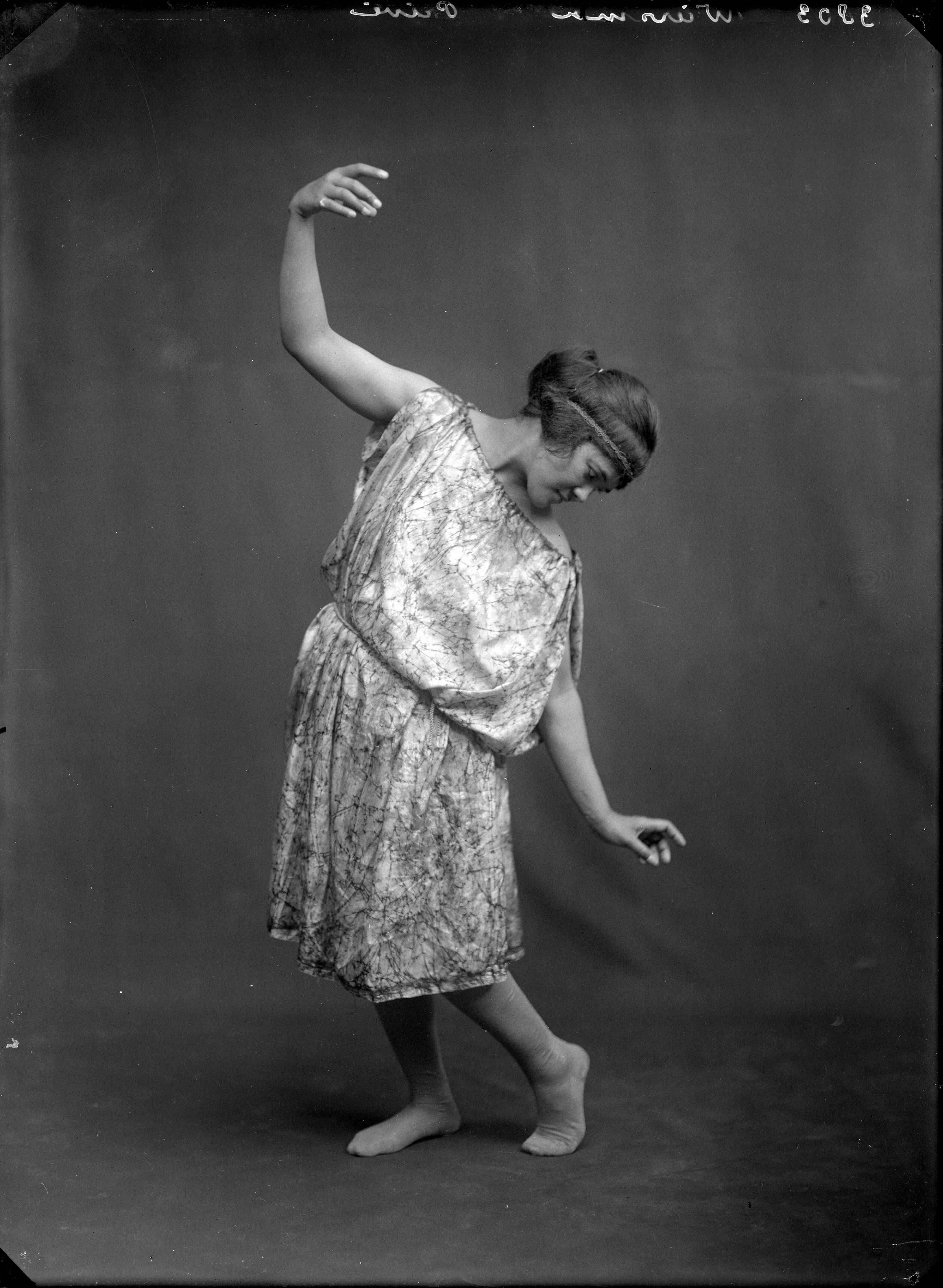 Berg, van den (BERG 050) — Studio-opnames. Een vrouw in danshouding in een wijde satijnen tuniekachtige jurk met koord. 3803 Wiersma privé. Haarlem, Nederland 1918-1930. — Foto: Berg, Th.C.J. van den / Spaarnestad Photo (05887). Licentie: Set B: Rechtenvrij / Publiek Domein. Bron: Nationaal Archief. http://hdl.handle.net/10648/35429da7-c558-a382-e063-6df0900a6686