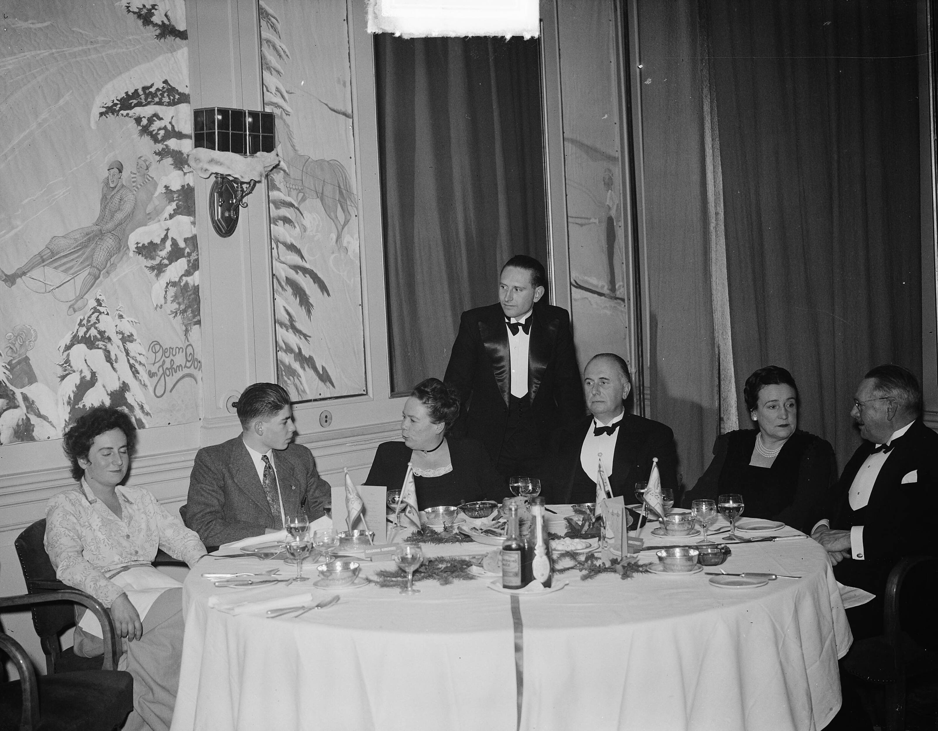 Fotocollectie Anefo — Kerstdiner mevrouw Rooselaar Amstel 194. Groepje diner Pays Bas te Utrecht — Foto: Averink, […] / Anefo. Licentie: Set B: Rechtenvrij / Publiek Domein. Bron: Nationaal Archief. http://hdl.handle.net/10648/a8c1b2bc-d0b4-102d-bcf8-003048976d84