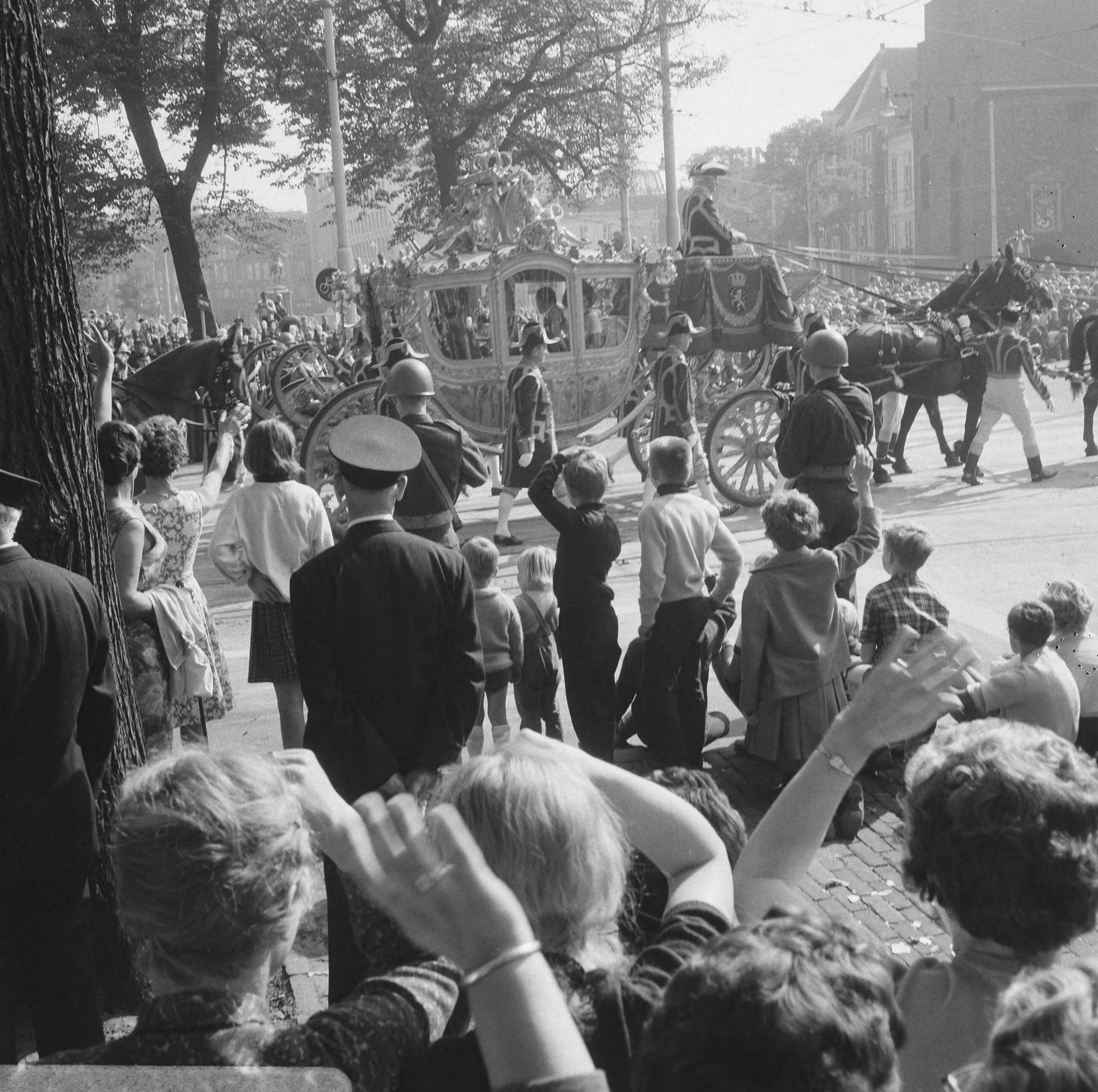Prinsjesdag 1966 in Den Haag — Mensen zwaaiend naar de Gouden Koets op weg naar de Ridderzaal — Foto: Kroon, Ron / Anefo. Licentie: Set B: Rechtenvrij / Publiek Domein. Bron: Nationaal Archief. http://hdl.handle.net/10648/aafd1e04-d0b4-102d-bcf8-003048976d84