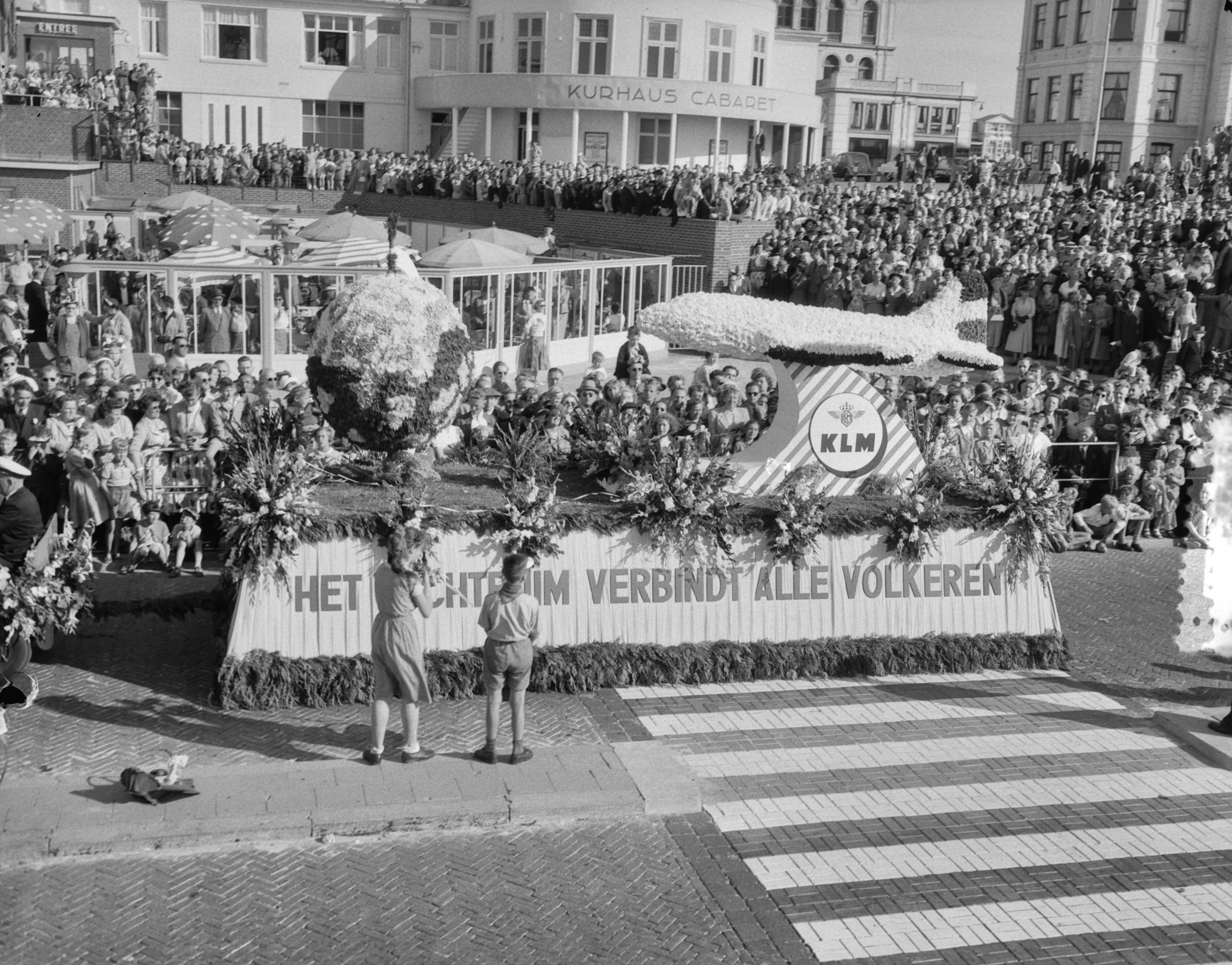 Bloemencorso in Den Haag 1953 — Bloemencorso in Den Haag. Praalwagen van KLM met opschrift "Het luchtruim verbindt alle volkeren" voor het Kurhaus — Foto: Duinen, G.W. van / Anefo. Licentie: Set B: Rechtenvrij / Publiek Domein. Bron: Nationaal Archief. http://hdl.handle.net/10648/a910ba1a-d0b4-102d-bcf8-003048976d84