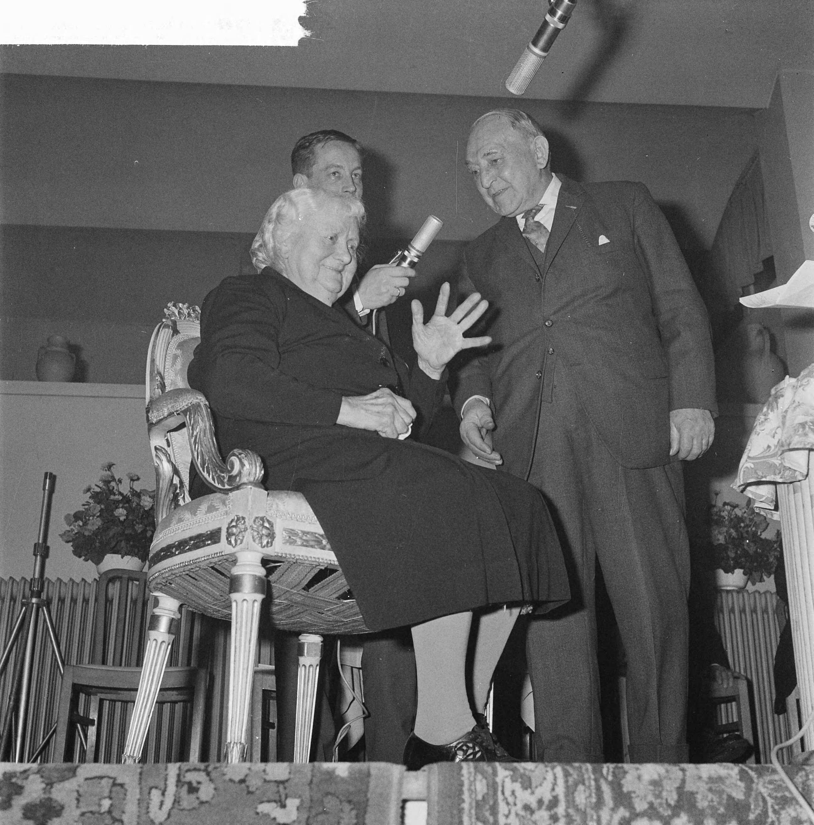 Fotocollectie Anefo — VARA-radioprogramma "Dit is uw Leven". mevrouw H. ter Hall-Köhler met dhr. H. E. Glazener. In de achtergrond met microfoon presentator Bert Garthoff — Foto: Nijs, Jac. de / Anefo. Licentie: Set B: Rechtenvrij / Publiek Domein. Bron: Nationaal Archief. http://hdl.handle.net/10648/a9f7eaca-d0b4-102d-bcf8-003048976d84
