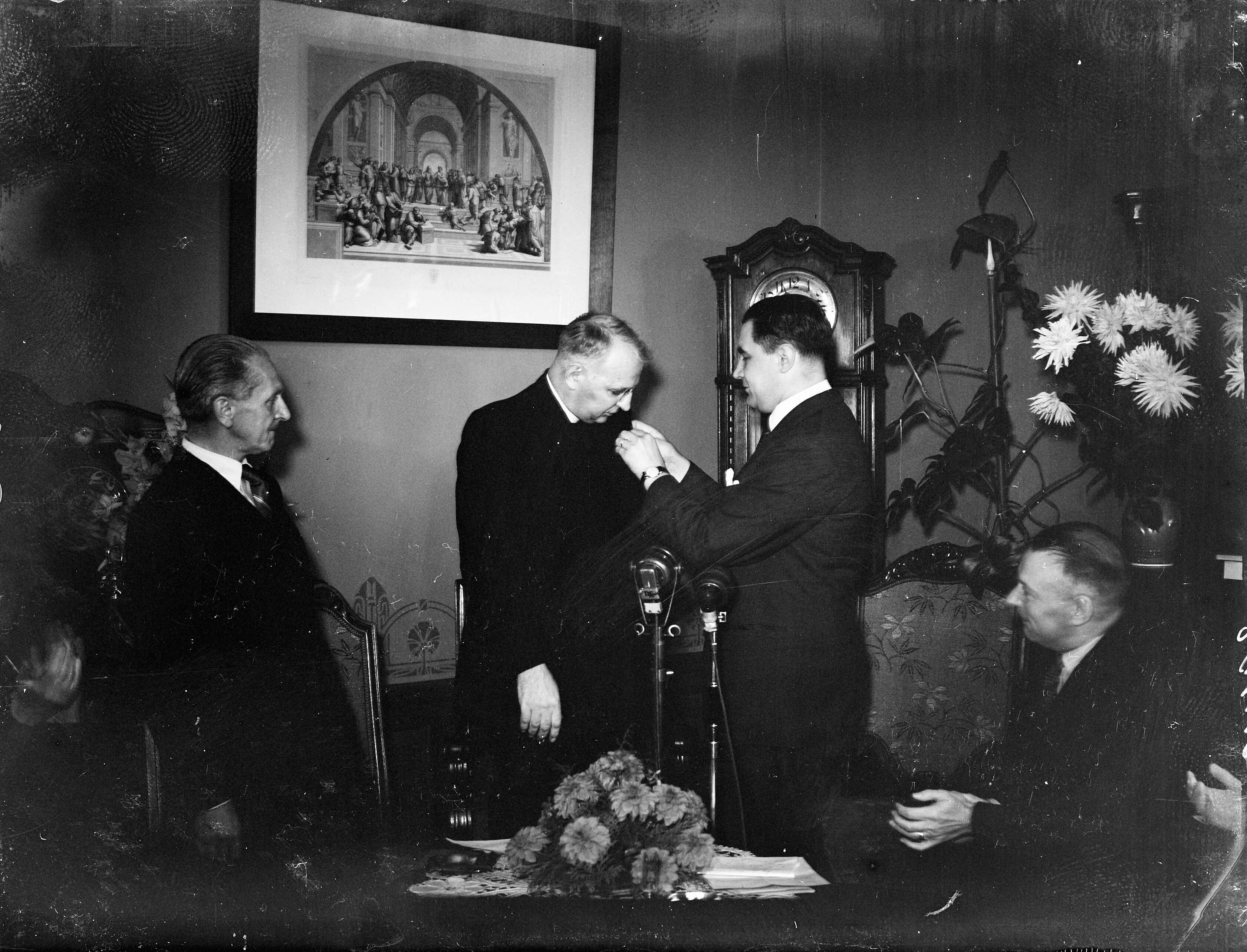 Fotocollectie Anefo — Pater Henri de Greeve wordt gedecoreerd door minister Sassen — Foto: Oorschot, […] van / Anefo. Licentie: Set B: Rechtenvrij / Publiek Domein. Bron: Nationaal Archief. http://hdl.handle.net/10648/a8bb552a-d0b4-102d-bcf8-003048976d84