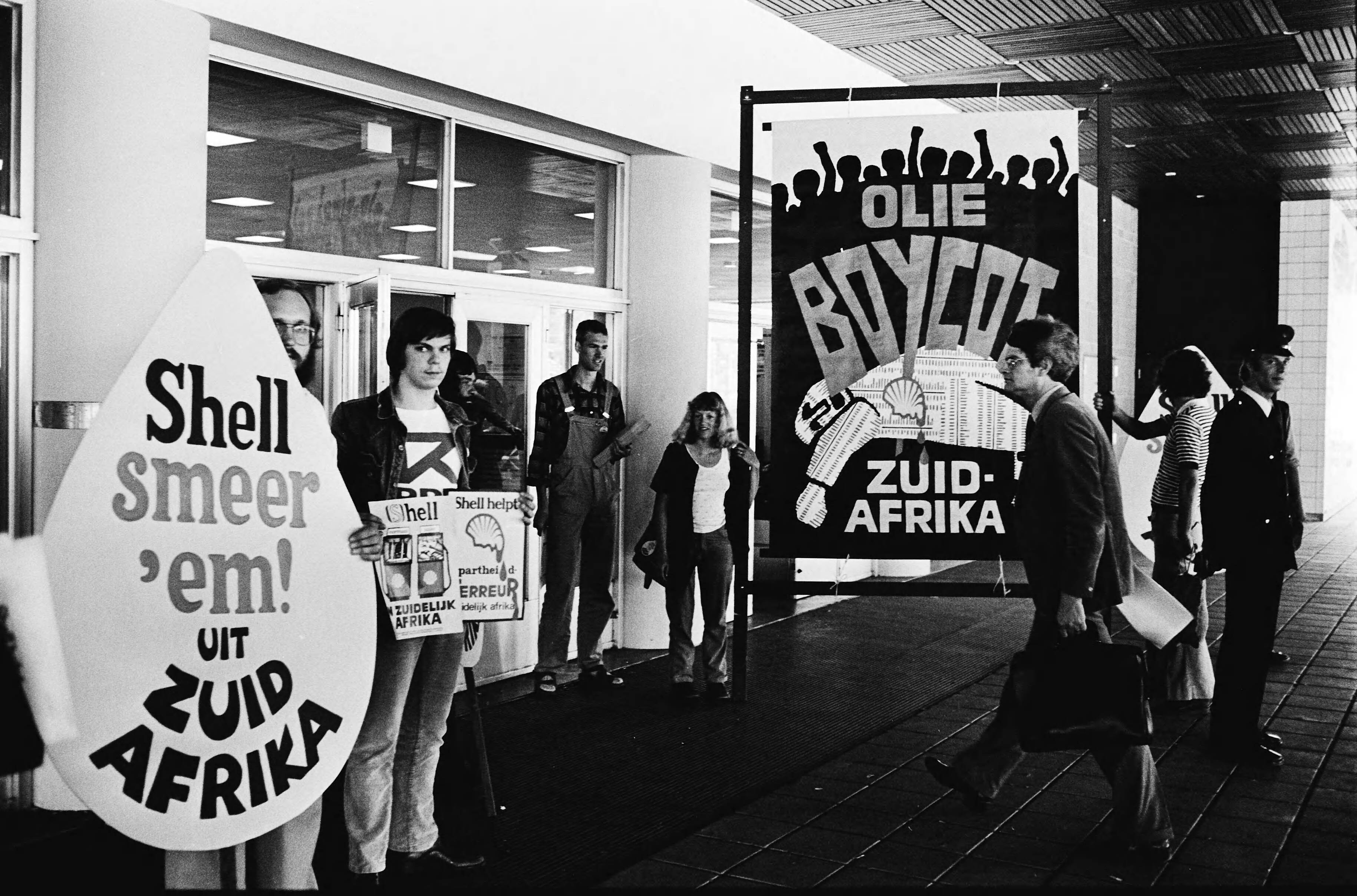 Fotocollectie Anefo — Shell aandeelhoudersvergadering in Congresgebouw in Den Haag ; demonstranten bij de ingang — Foto: Suyk, Koen / Anefo. Licentie: Set B: Rechtenvrij / Publiek Domein. Bron: Nationaal Archief. http://hdl.handle.net/10648/ace0bda2-d0b4-102d-bcf8-003048976d84