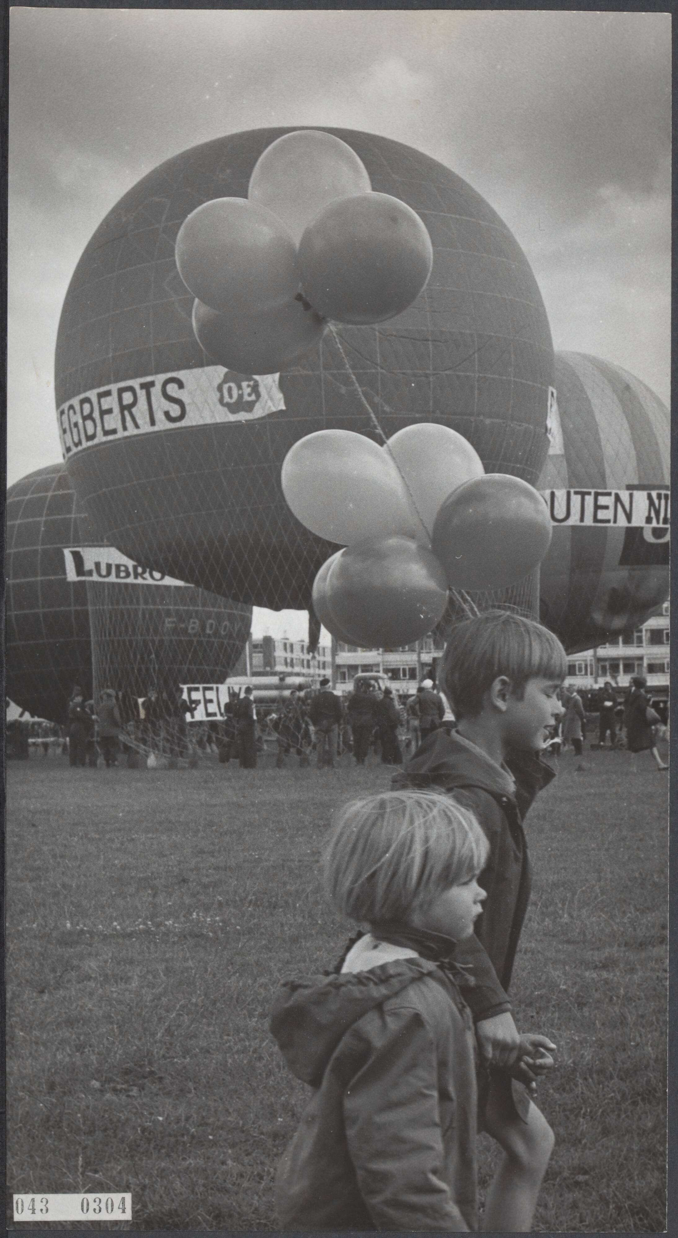 Fotocollectie Elsevier Binnenland — In Utrecht zijn zeven ballonnen uit 5 landen van start gegaan in een wedstrijd om de Trophee du Ballon Libre. In de voorgrond twee kinderen met ballonnen — Foto: Gelderen, Hugo van / Anefo. Licentie: Set B: Rechtenvrij / Publiek Domein. Bron: Nationaal Archief. http://hdl.handle.net/10648/adf8a646-d0b4-102d-bcf8-003048976d84
