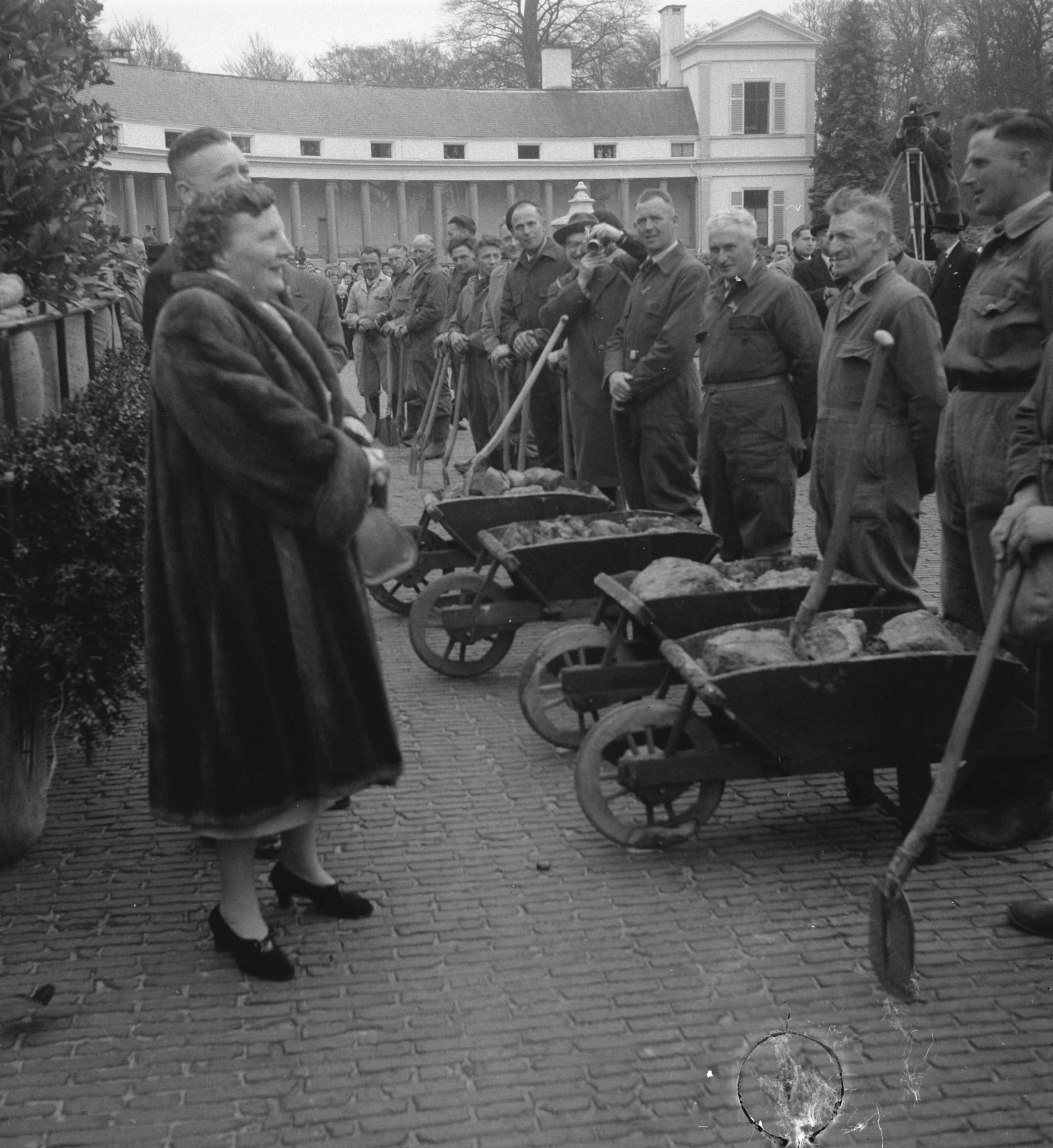 Koninginnedag 1956 — Defilé langs paleis Soestdijk ter gelegenheid van de verjaardag van koningin Juliana. Koningin Juliana praat met arbeiders met kruiwagens — Foto: Noske, J.D. / Anefo. Licentie: Set B: Rechtenvrij / Publiek Domein. Bron: Nationaal Archief. http://hdl.handle.net/10648/a9470eda-d0b4-102d-bcf8-003048976d84