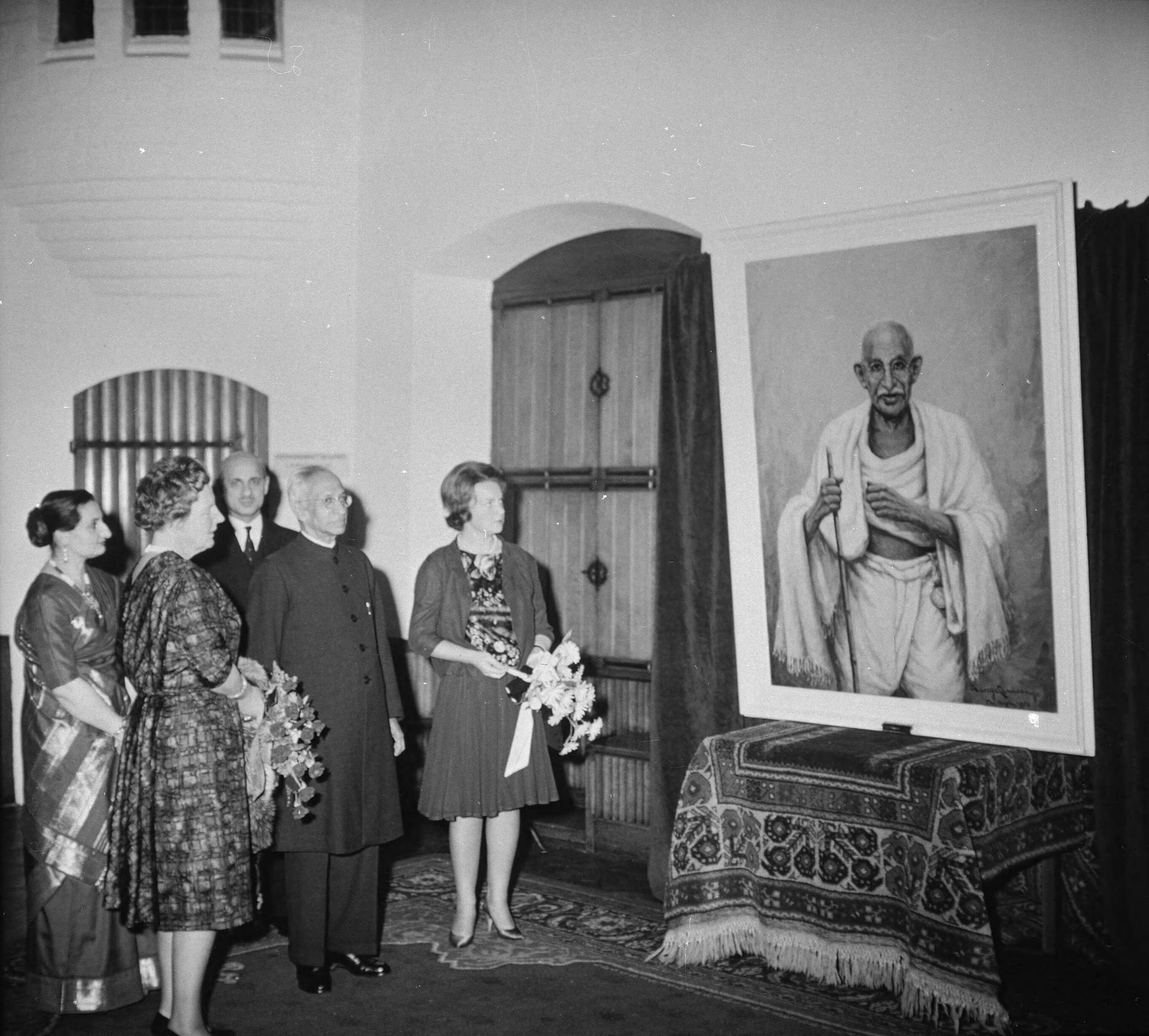 Fotocollectie RVD / Koninklijk Huis — Koningin Juliana en prinses Irene tijdens Tagore-herdenking in de Ridderzaal te Den Haag, bij een schilderij van Ghandi, donderdag 19 oktober 1961 — Foto: Rousel (repro) / RVD. Licentie: Set B: Rechtenvrij / Publiek Domein. Bron: Nationaal Archief. http://hdl.handle.net/10648/afb4dafe-d0b4-102d-bcf8-003048976d84