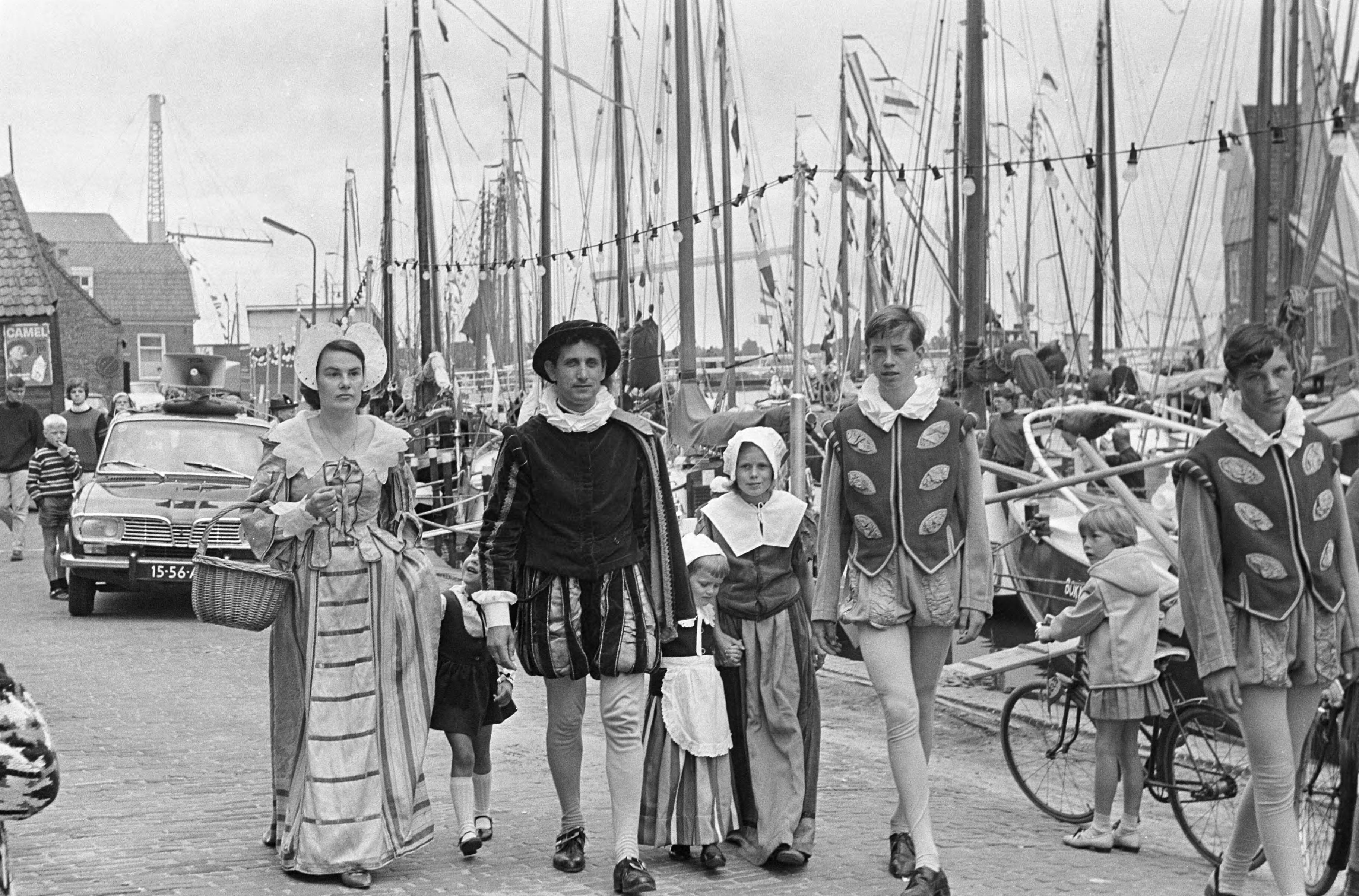 Fotocollectie Anefo — Feest te Monnickendam, een gezin in historische kledij, op de achtergrond de gepavoiseerde vloot — Foto: Evers, Joost / Anefo. Licentie: Set B: Rechtenvrij / Publiek Domein. Bron: Nationaal Archief. http://hdl.handle.net/10648/aaf1e746-d0b4-102d-bcf8-003048976d84
