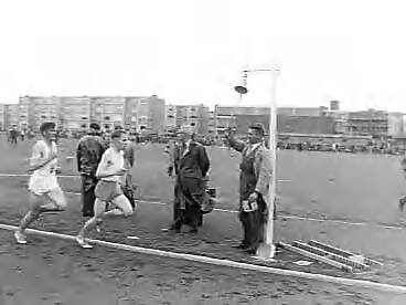 Fotocollectie Anefo — Nederlandse atletiekkampioenschappen te Den Haag. Bel laatste ronde bij een hardlopen-onderdeel wordt geluid — Foto: Noske, J.D. / Anefo. Licentie: Set B: Rechtenvrij / Publiek Domein. Bron: Nationaal Archief. http://hdl.handle.net/10648/a96726b6-d0b4-102d-bcf8-003048976d84