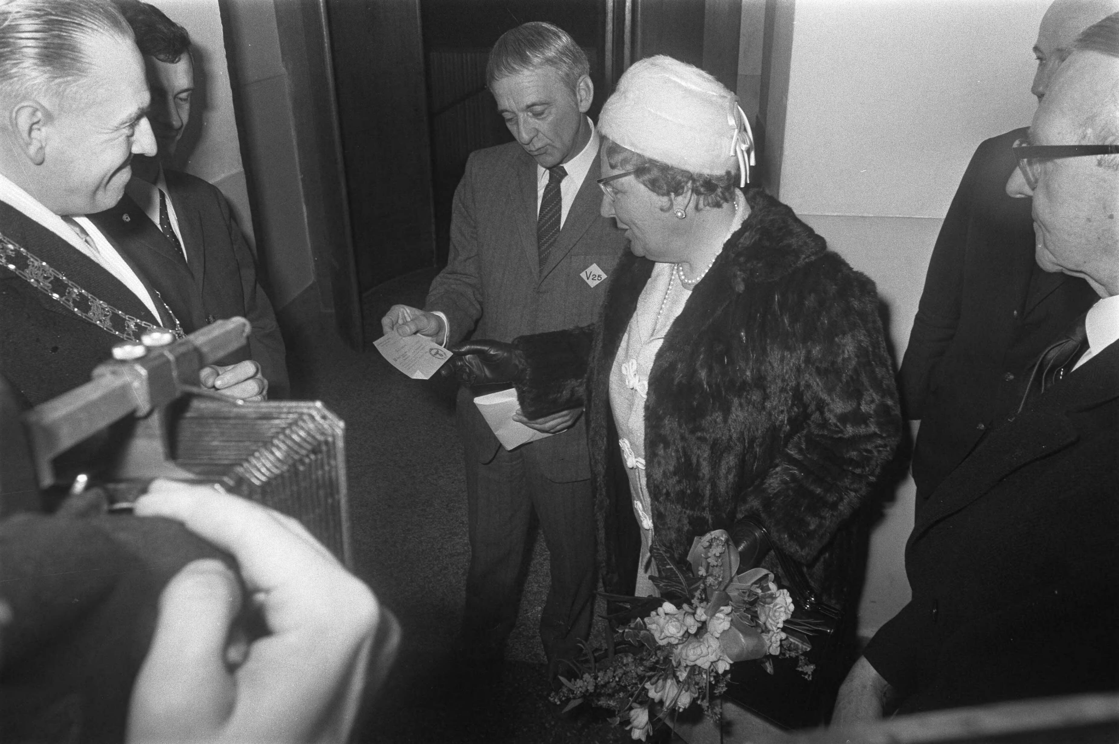Herdenking in Leeuwarden van 25 jaar bevrijding van Friesland in aanwezigheid van koningin Juliana — Koningin Juliana ontvangt in het beursgebouw van Leeuwarden van de heer Hallema een 'Ausweiss'. Links burgemeester van Leeuwarden Brandsma — Foto: Fotograaf Onbekend / Anefo. Licentie: Set B: Rechtenvrij / Publiek Domein. Bron: Nationaal Archief. http://hdl.handle.net/10648/ab943b9a-d0b4-102d-bcf8-003048976d84
