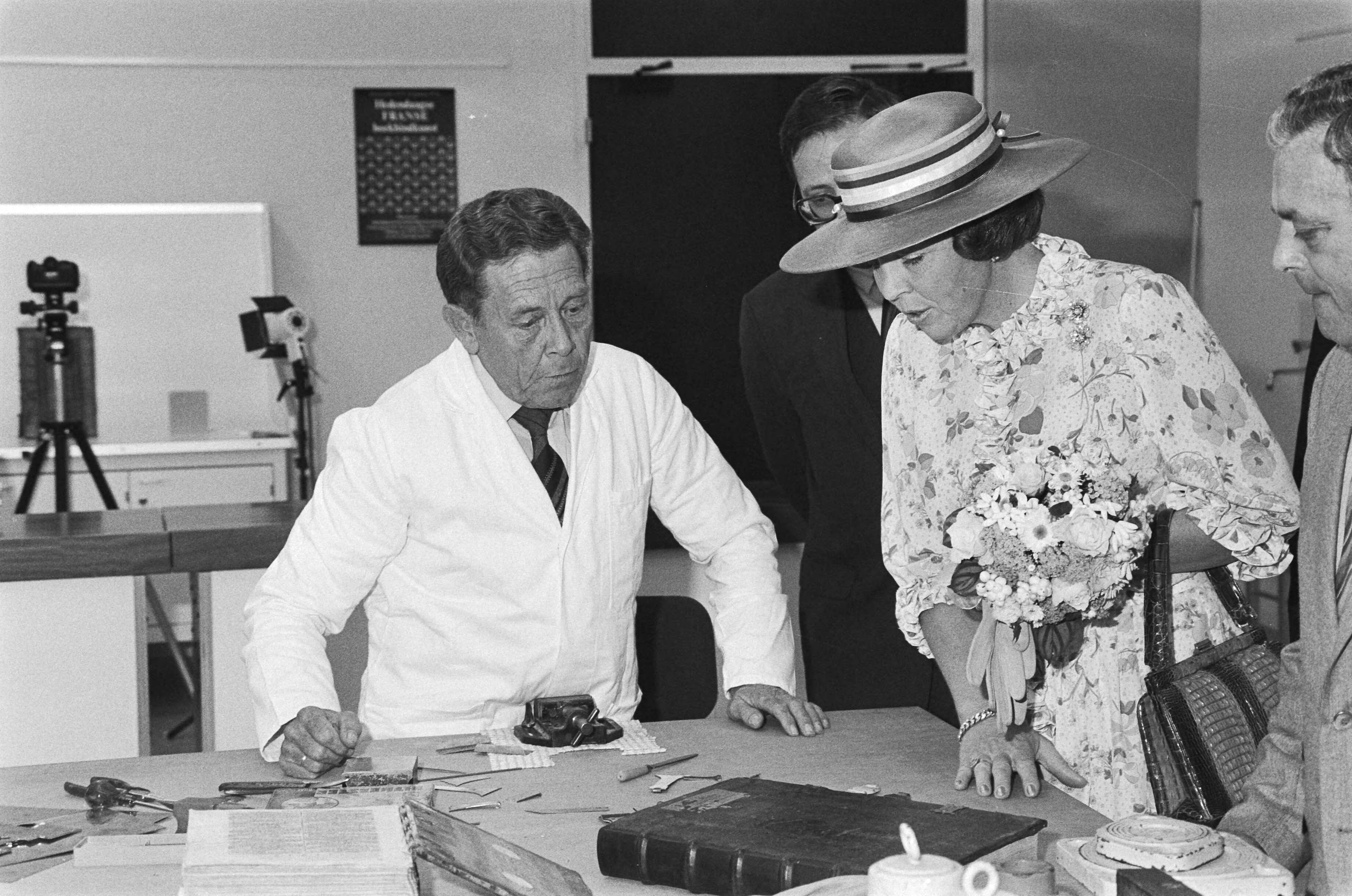Koningin Beatrix opent de Koninklijke Bibliotheek in Den Haag — Koningin Beatrix op de boekenrestauratie-afdeling — Foto: Dijk, Hans van / Anefo. Licentie: Set B: Rechtenvrij / Publiek Domein. Bron: Nationaal Archief. http://hdl.handle.net/10648/ad1f400e-d0b4-102d-bcf8-003048976d84