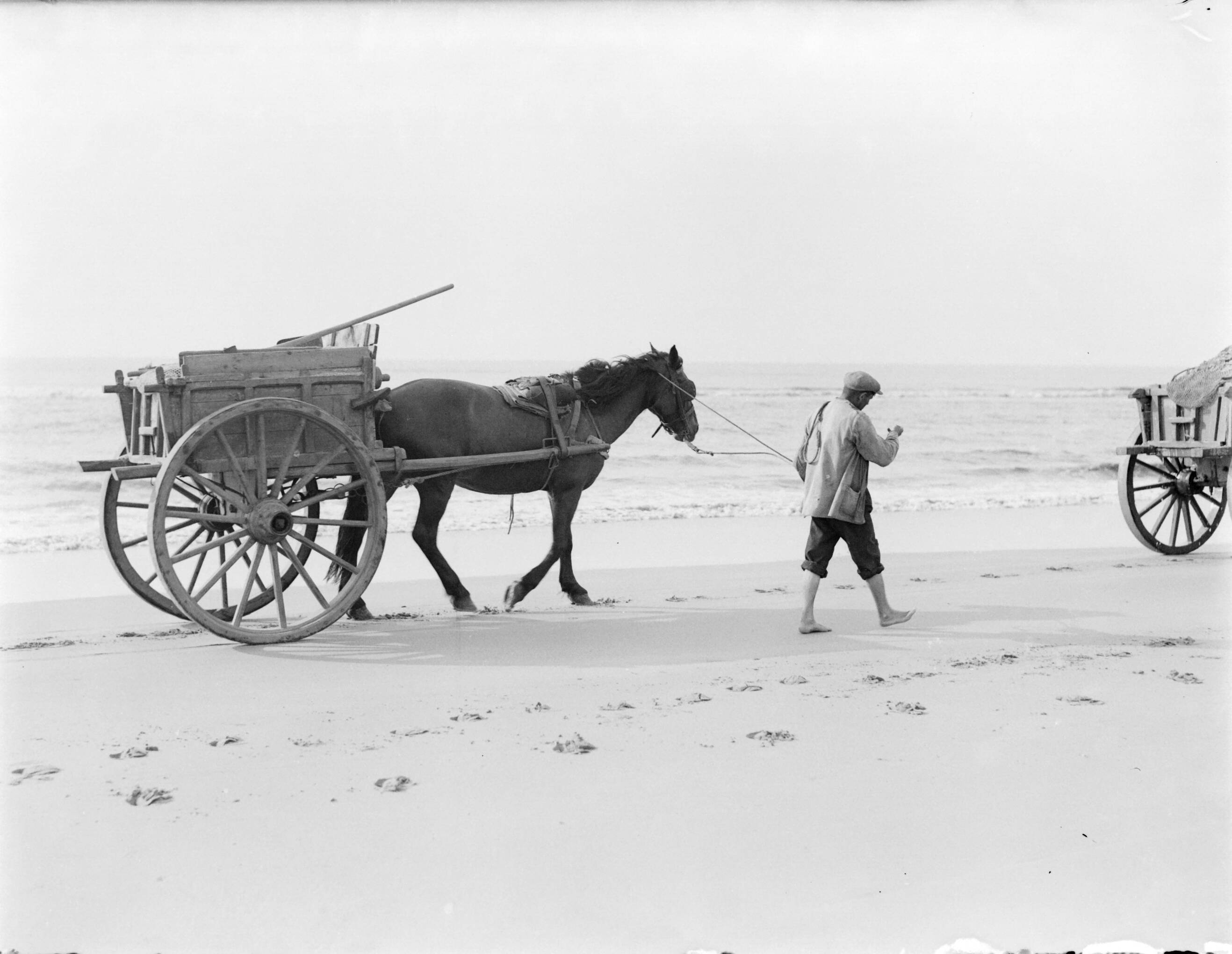 Reportage fotomodel — Een schelpenkar met lopend een man ervoor op het strand van Zandvoort — Foto: Poll, Willem van de. Licentie: Set B: Rechtenvrij / Publiek Domein. Bron: Nationaal Archief. http://hdl.handle.net/10648/aea7fcfe-d0b4-102d-bcf8-003048976d84