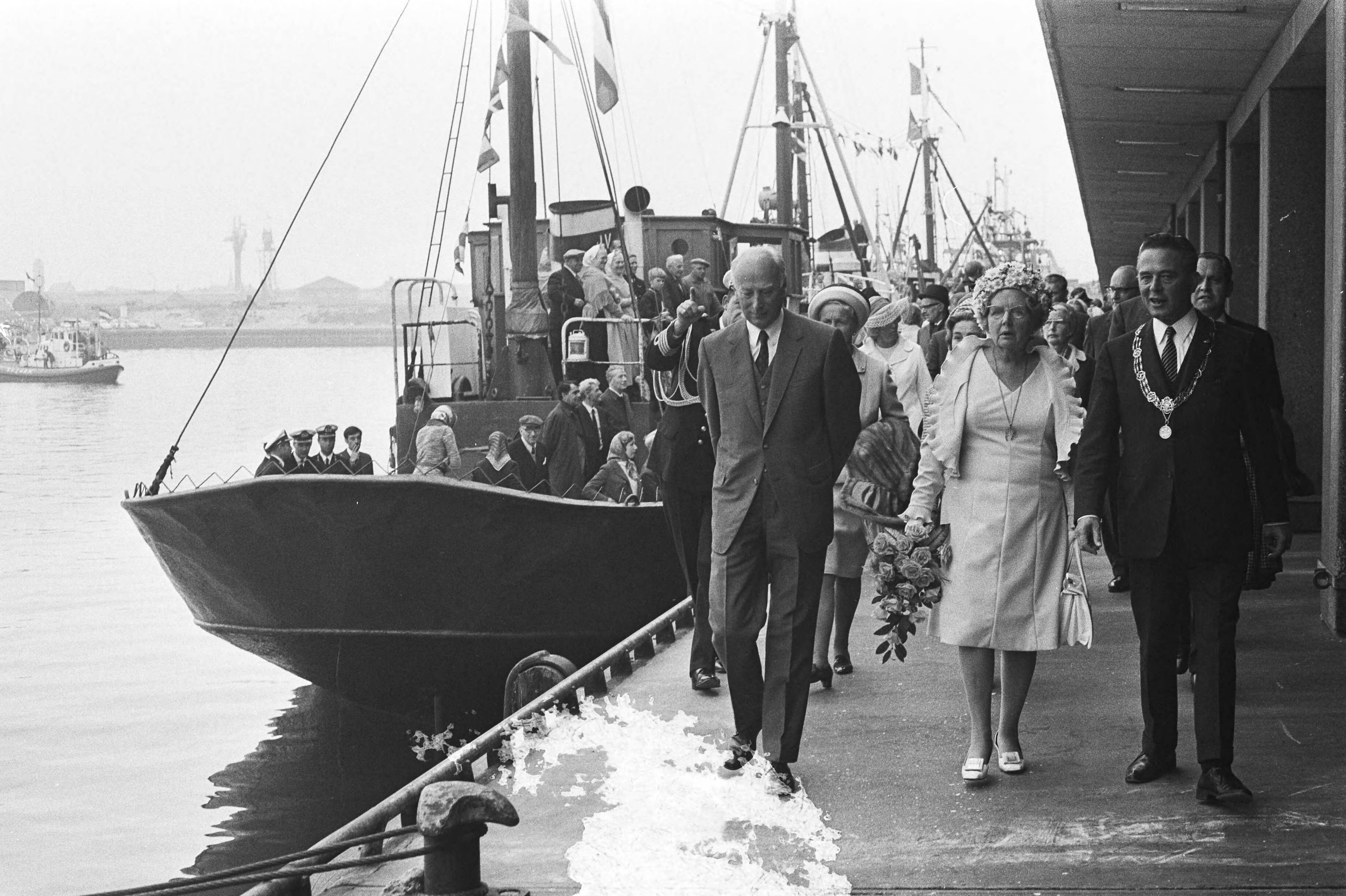 Hare Majesteit opent Havenmond, Scheveningen — Koningin Juliana (m), minister Bakker (l) en burgemeester Marijnen (r) wandelen door de haven — Foto: Fotograaf Onbekend / Anefo. Licentie: Set B: Rechtenvrij / Publiek Domein. Bron: Nationaal Archief. http://hdl.handle.net/10648/abc04320-d0b4-102d-bcf8-003048976d84
