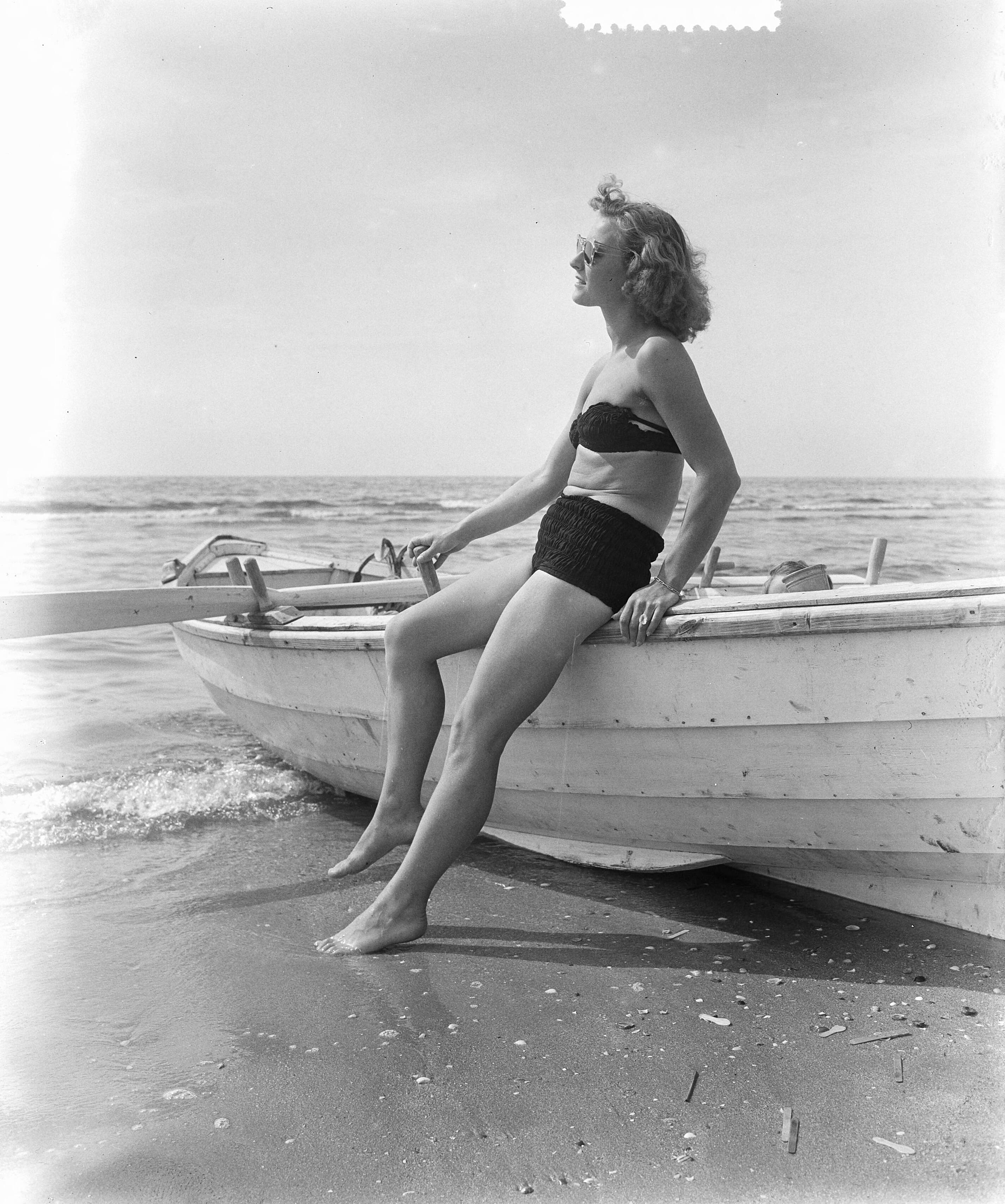 Fotocollectie Anefo — Zomerplaatjes aan strand van Zandvoort. Moeder poseert alleen bij roeiboot — Foto: Pot, Harry / Anefo. Licentie: Set B: Rechtenvrij / Publiek Domein. Bron: Nationaal Archief. http://hdl.handle.net/10648/a90e596e-d0b4-102d-bcf8-003048976d84