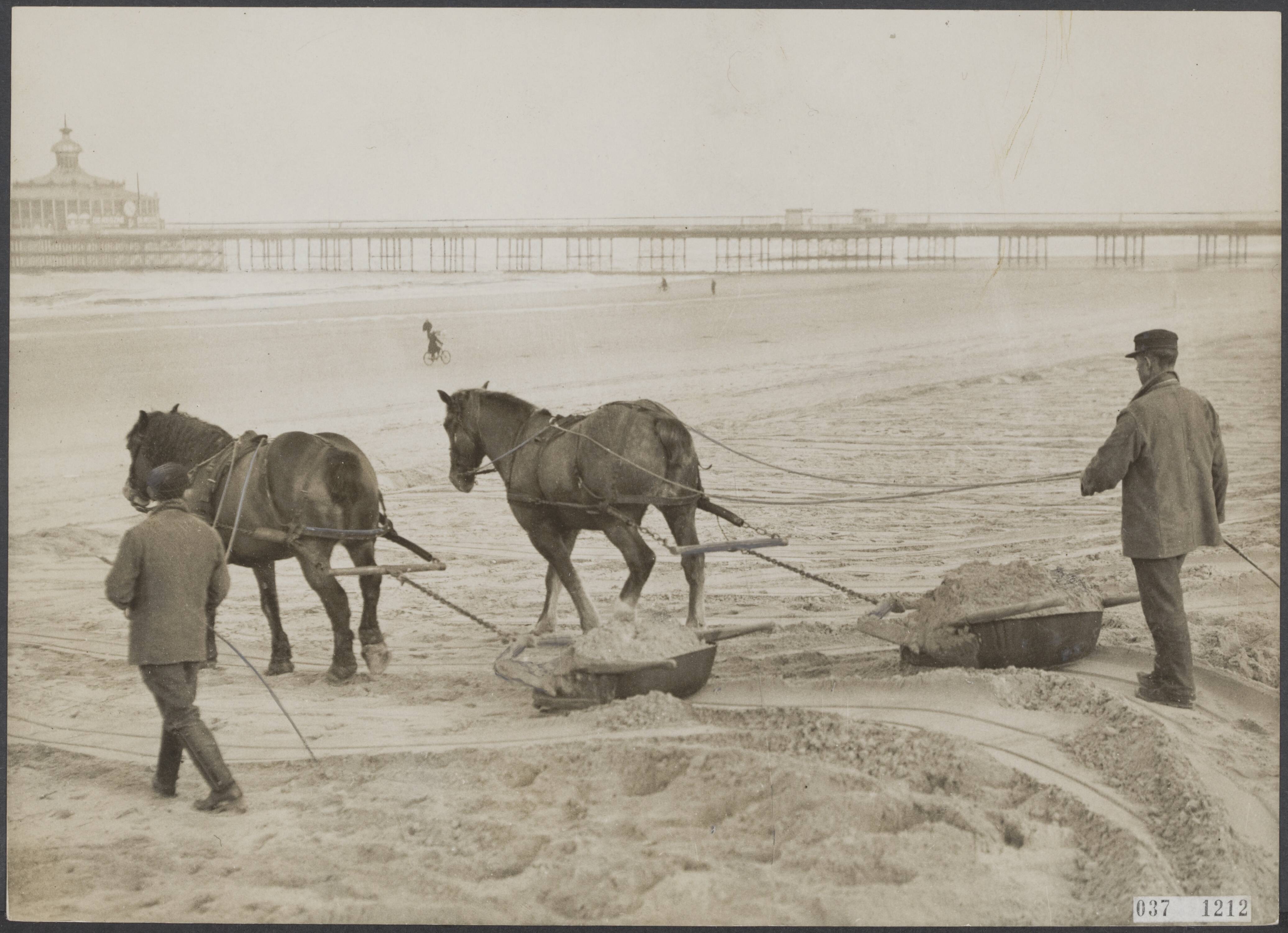 Fotocollectie Elsevier Binnenland — Gedurende de winter is het zand hoog tegen de boulevard te Scheveningen gewaaid. Thans wordt het door gemeente werklieden met zandploegen weggehaald — Foto: N.V. Polygoon. Licentie: Set B: Rechtenvrij / Publiek Domein. Bron: Nationaal Archief. http://hdl.handle.net/10648/adefdcbe-d0b4-102d-bcf8-003048976d84