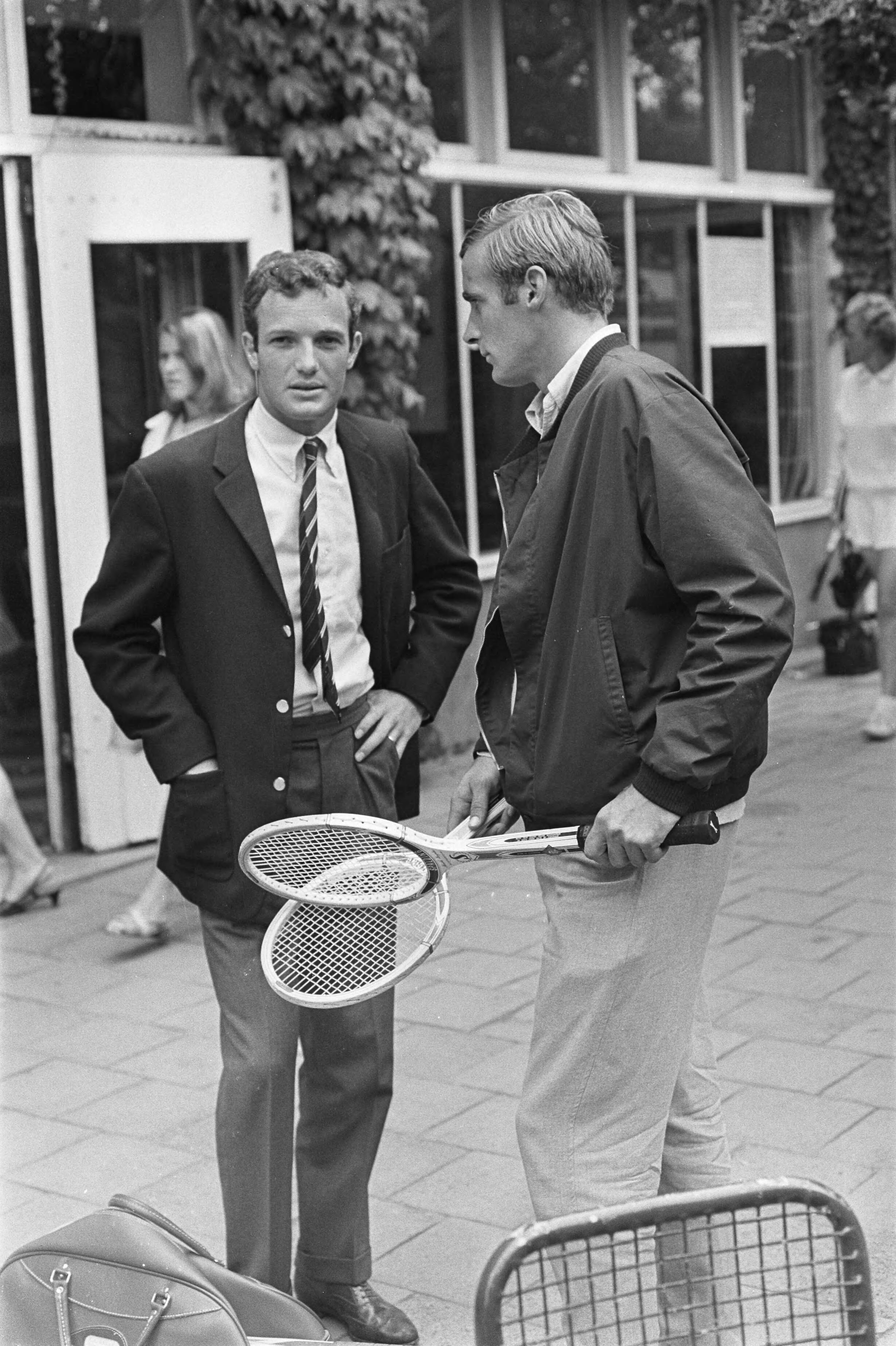 Fotocollectie Anefo — Nederlandse tenniskampioenschappen op de METS-banen te Scheveningen. Tom Okker (links) in gesprek met Jan Hajer — Foto: Fotograaf Onbekend / Anefo. Licentie: Set B: Rechtenvrij / Publiek Domein. Bron: Nationaal Archief. http://hdl.handle.net/10648/ab4a24f6-d0b4-102d-bcf8-003048976d84