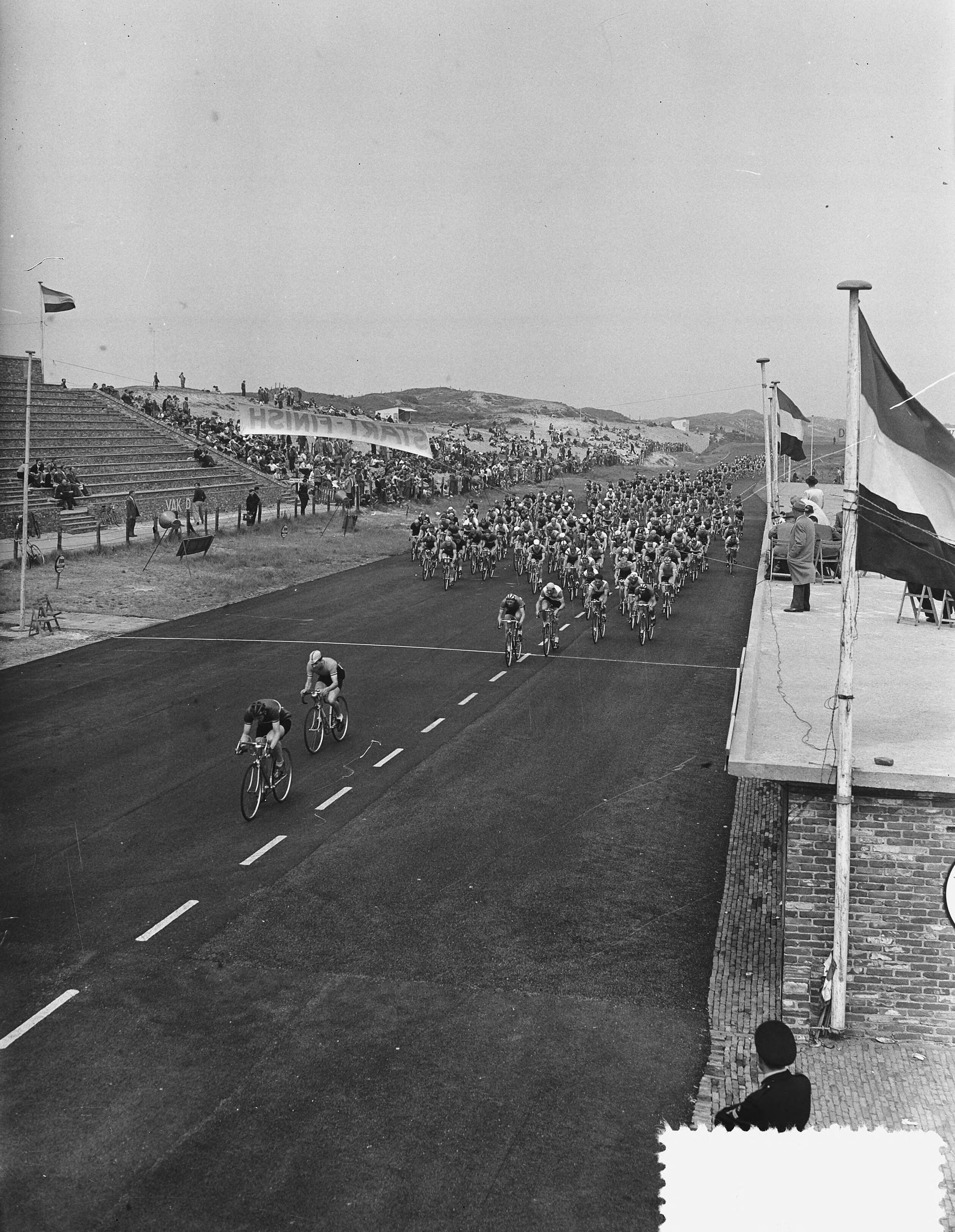 Fotocollectie Anefo — Nederlands kampioenschap wielrennen op de weg voor amateurs op het circuit van Zandvoort. Start — Foto: Fotograaf Onbekend / Anefo. Licentie: Set B: Rechtenvrij / Publiek Domein. Bron: Nationaal Archief. http://hdl.handle.net/10648/a9259476-d0b4-102d-bcf8-003048976d84