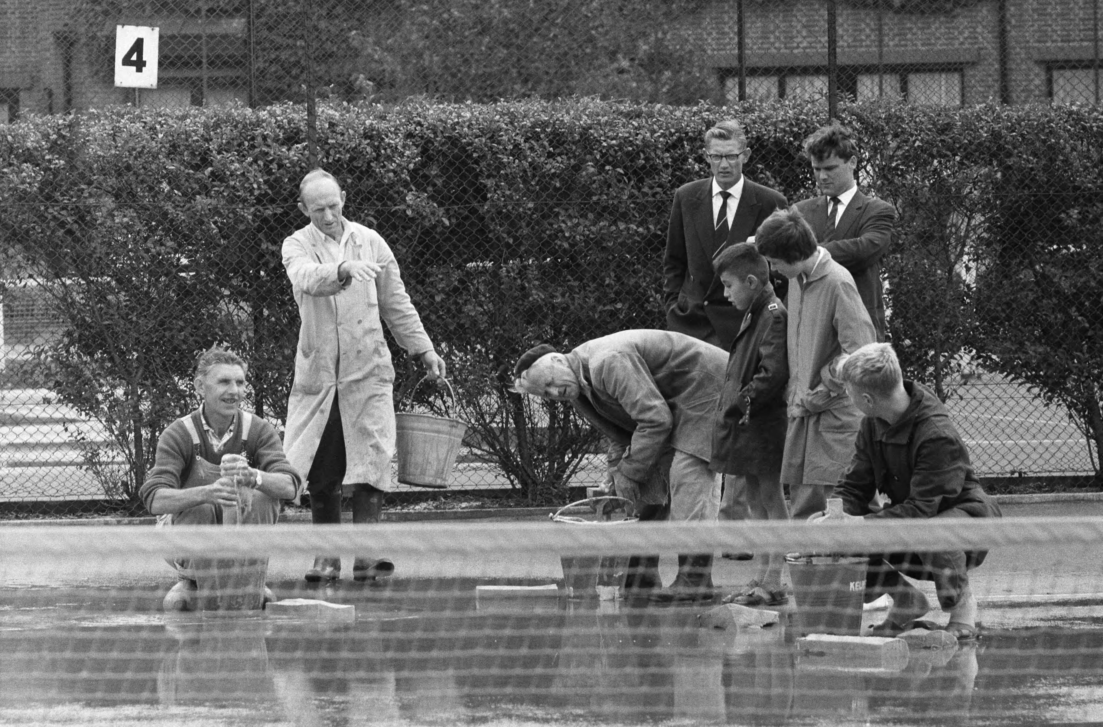 Fotocollectie Anefo — Nederlandse tenniskampioenschappen op de METS-banen te Scheveningen. Baan 2 wordt met dweilen drooggemaakt — Foto: Pot, Harry / Anefo. Licentie: Set B: Rechtenvrij / Publiek Domein. Bron: Nationaal Archief. http://hdl.handle.net/10648/a9b6a5b0-d0b4-102d-bcf8-003048976d84