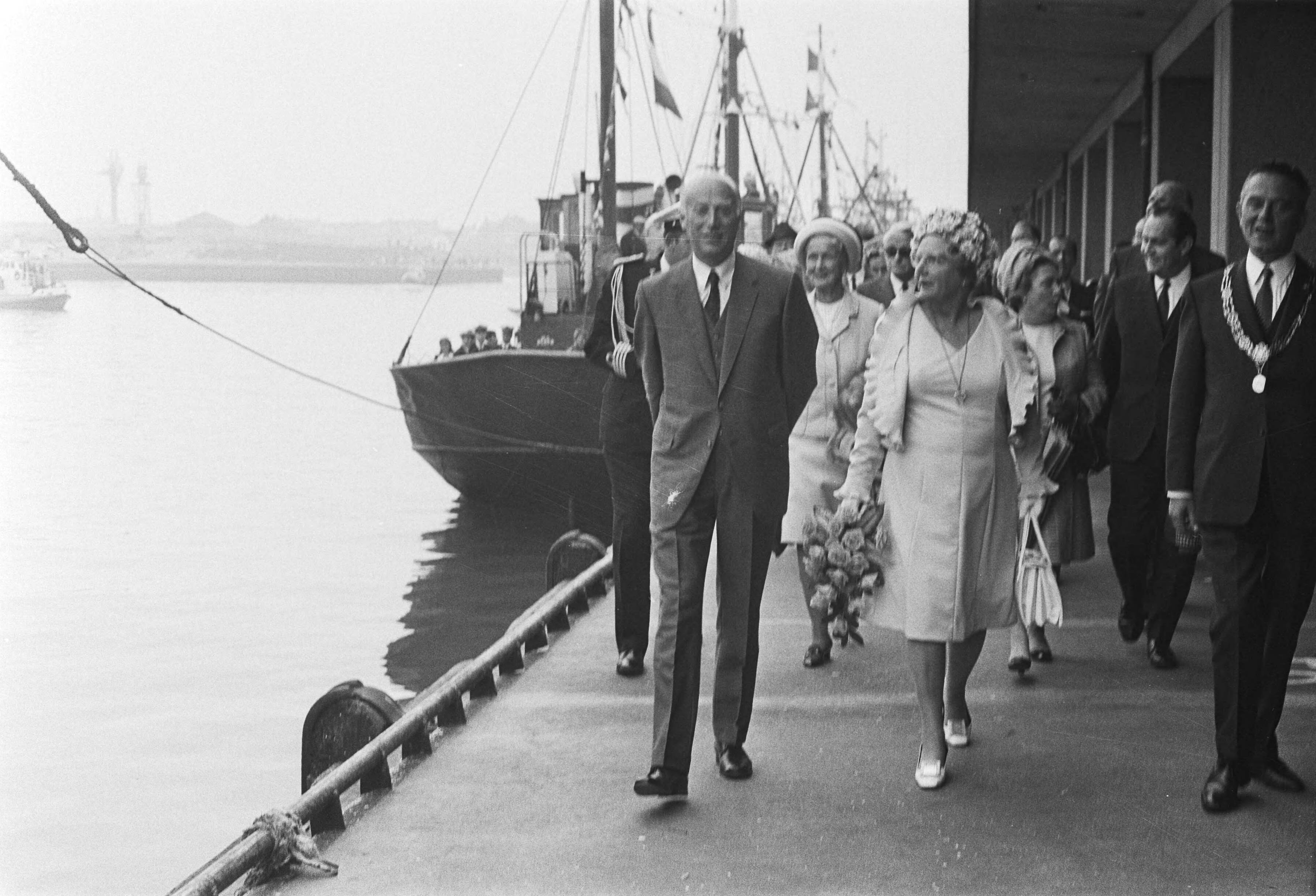 Hare Majesteit opent Havenmond, Scheveningen — Koningin Juliana (m), minister Bakker (l) en burgemeester Marijnen (r) wandelen door de haven — Foto: Fotograaf Onbekend / Anefo. Licentie: Set B: Rechtenvrij / Publiek Domein. Bron: Nationaal Archief. http://hdl.handle.net/10648/abc048f2-d0b4-102d-bcf8-003048976d84