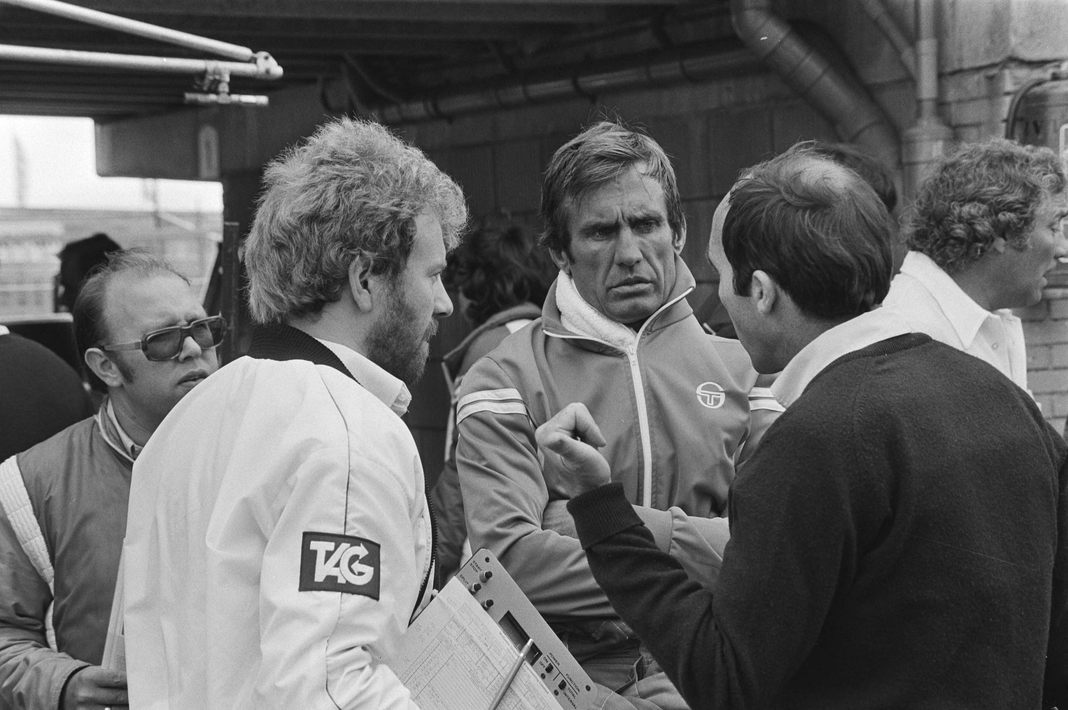Training op het Circuit van Zandvoort i.v.m. de Grand Prix van aanstaande zondag — Teameigenaar Frank Williams (rechts) in gesprek met Williams-Ford Formule 1coureur Carlos Reutemann (midden) tijdens de training van de Grand Prix Formule 1 van Zandvoort in 1981 — Foto: Dijk, Hans van / Anefo. Licentie: Set B: Rechtenvrij / Publiek Domein. Bron: Nationaal Archief. http://hdl.handle.net/10648/ad025b24-d0b4-102d-bcf8-003048976d84