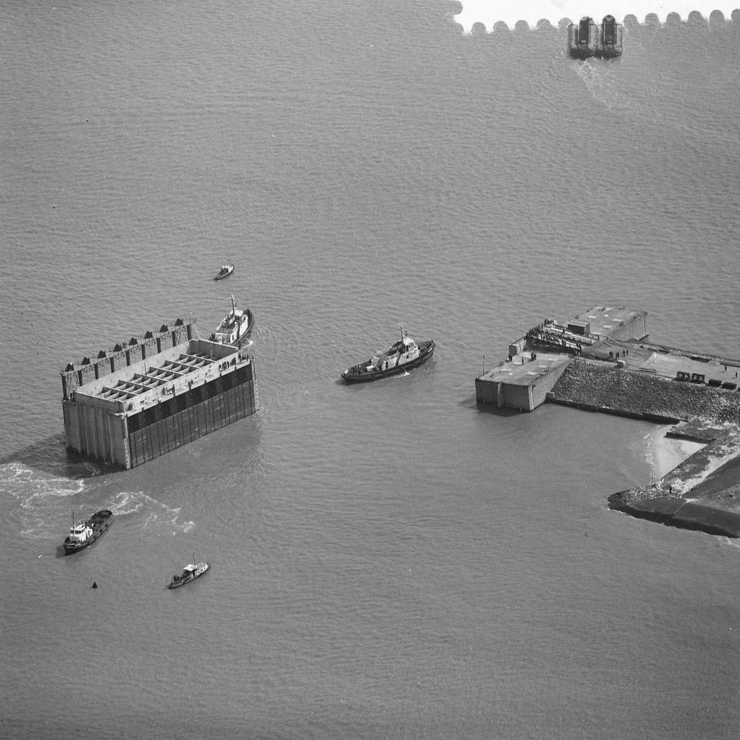 Fotocollectie Anefo — Luchtopnamen. Invaren van caissons in het Veerse Gat — Foto: Slagboom, Anton / Anefo. Licentie: Set B: Rechtenvrij / Publiek Domein. Bron: Nationaal Archief. http://hdl.handle.net/10648/a9d10bb2-d0b4-102d-bcf8-003048976d84
