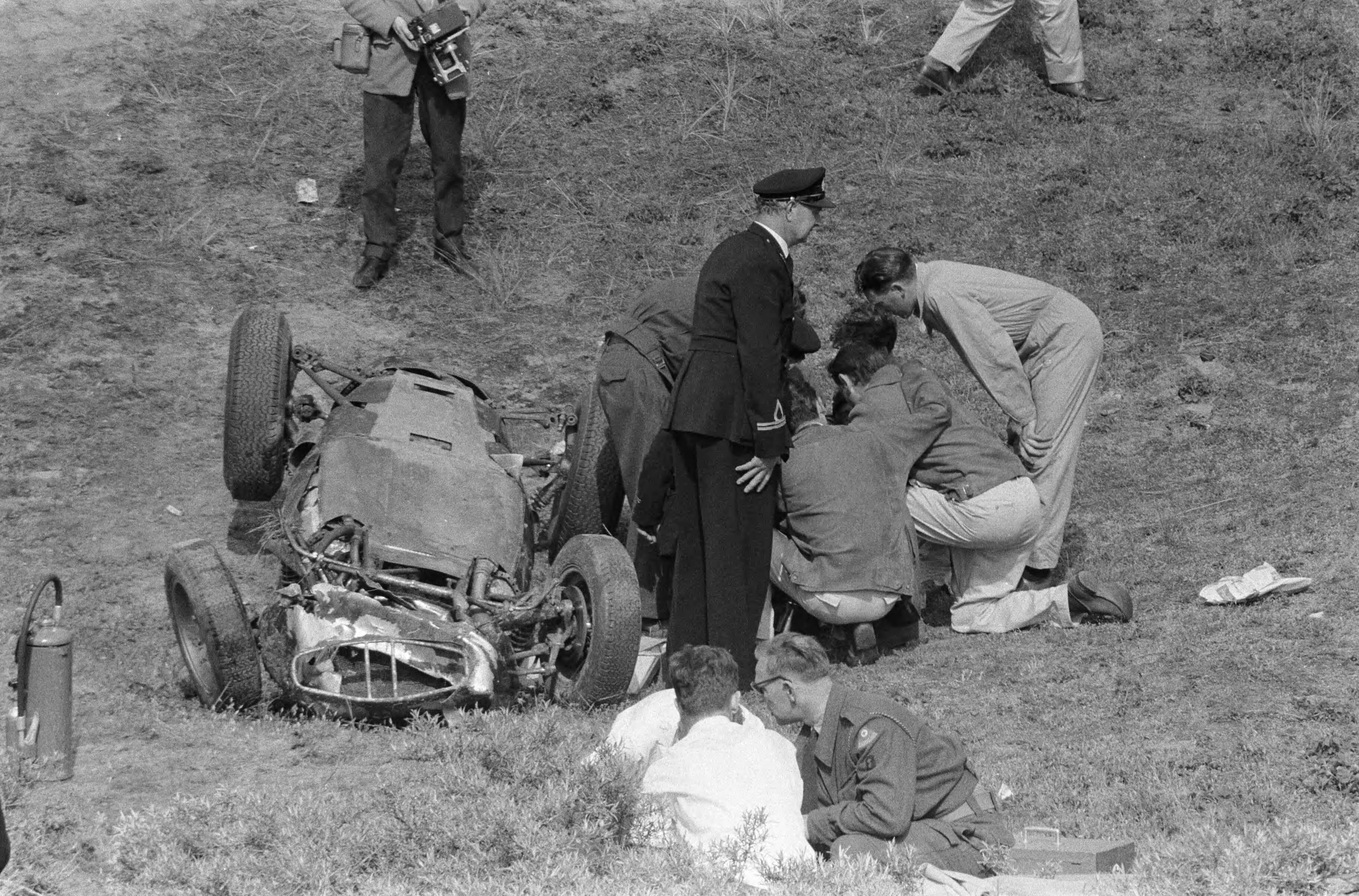 Autoraces op het circuit van Zandvoort. Dan Gurney wandelt terug naar de pits nadat hij in de Tarzanbocht rechtuit is gereden en over de hekken is gevlogen met zijn BRM F1 wagen door een defect aan de remmen. Hierbij kwam jammerlijk een jonge toeschouwer — Grote Prijs van Nederland op het circuit van Zandvoort. De verongelukte F1 BRM (wegens een defect aan de remmen) van de Amerikaan Dan Gurney. Hij overleeft de klap, maar een jonge toeschouwer komt om het leven. — Foto: Fotograaf Onbekend / Anefo. Licentie: Set B: Rechtenvrij / Publiek Domein. Bron: Nationaal Archief. http://hdl.handle.net/10648/a9b114ce-d0b4-102d-bcf8-003048976d84
