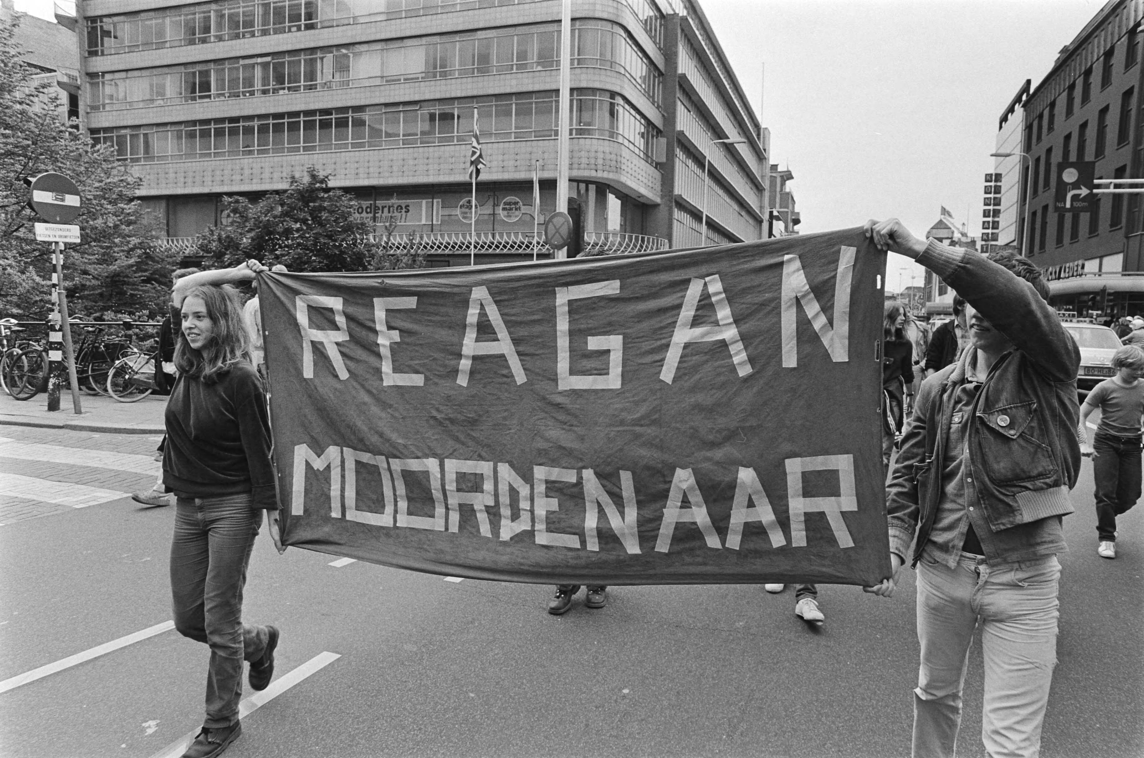 Fotocollectie Anefo — Demonstratie tegen Amerikaanse inmenging en El Salvador Utrecht; demonstranten met spandoek "Reagan moordenaar" — Foto: Antonisse, Marcel / Anefo. Licentie: Set B: Rechtenvrij / Publiek Domein. Bron: Nationaal Archief. http://hdl.handle.net/10648/acfdef4e-d0b4-102d-bcf8-003048976d84