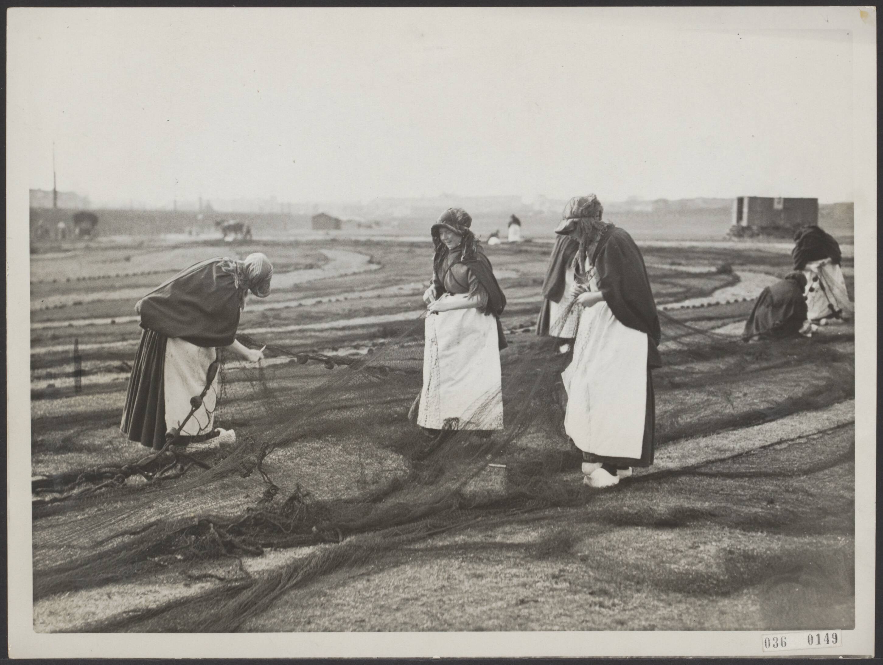 Fotocollectie Elsevier Binnenland — In Scheveningen is men thans druk bezig de netten die schade hebben opgelopen met de visvangst, te herstellen. Nettenboetsters in hun typische klederdracht bezig de netten te herstellen — Foto: N.V. Polygoon. Licentie: Set B: Rechtenvrij / Publiek Domein. Bron: Nationaal Archief. http://hdl.handle.net/10648/adebf306-d0b4-102d-bcf8-003048976d84