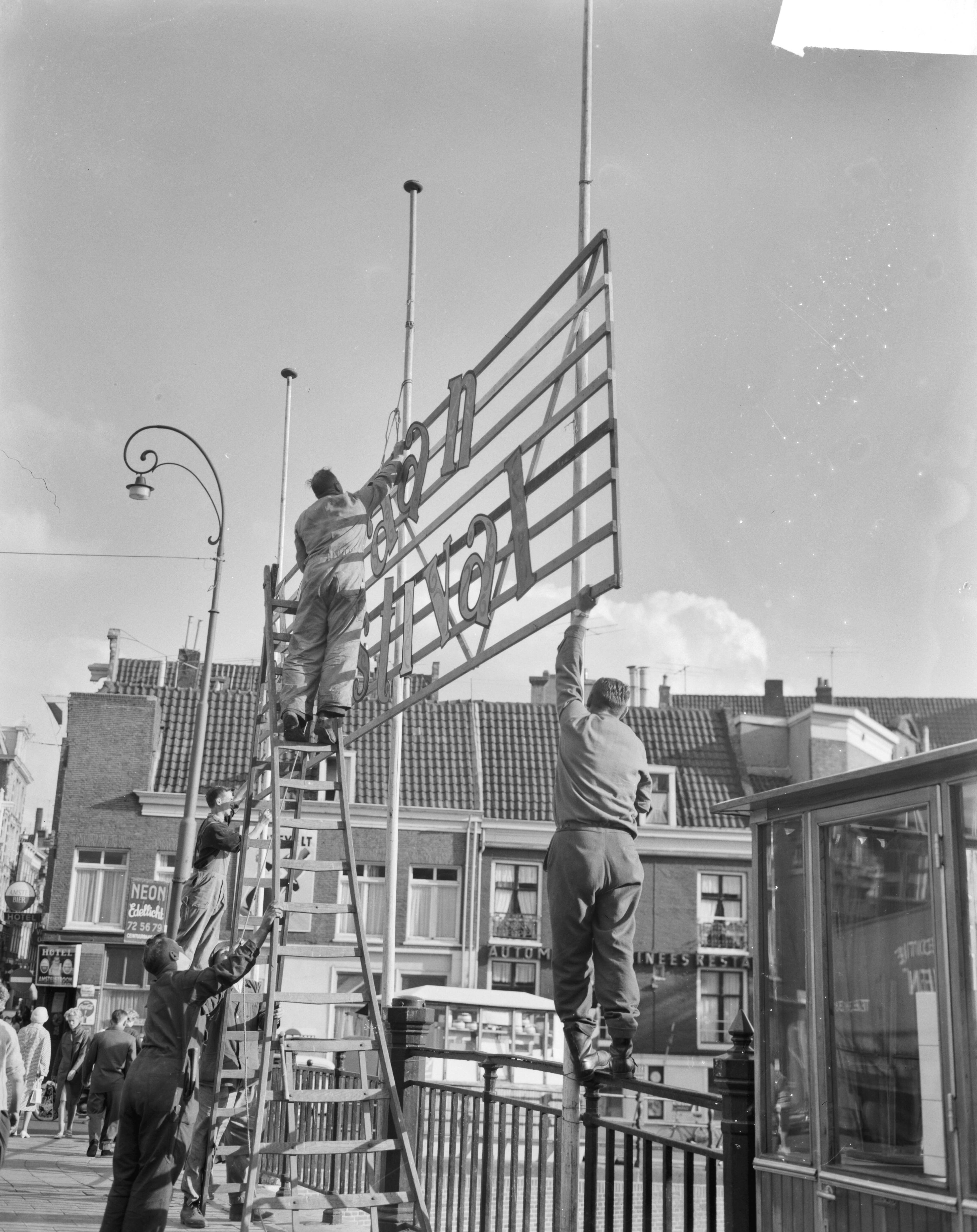 Fotocollectie Anefo — Jordaanfestival in Amsterdam, op de Rozengracht wordt versiering aangebracht — Foto: Gelderen, Hugo van / Anefo. Licentie: Set B: Rechtenvrij / Publiek Domein. Bron: Nationaal Archief. http://hdl.handle.net/10648/aa16c094-d0b4-102d-bcf8-003048976d84