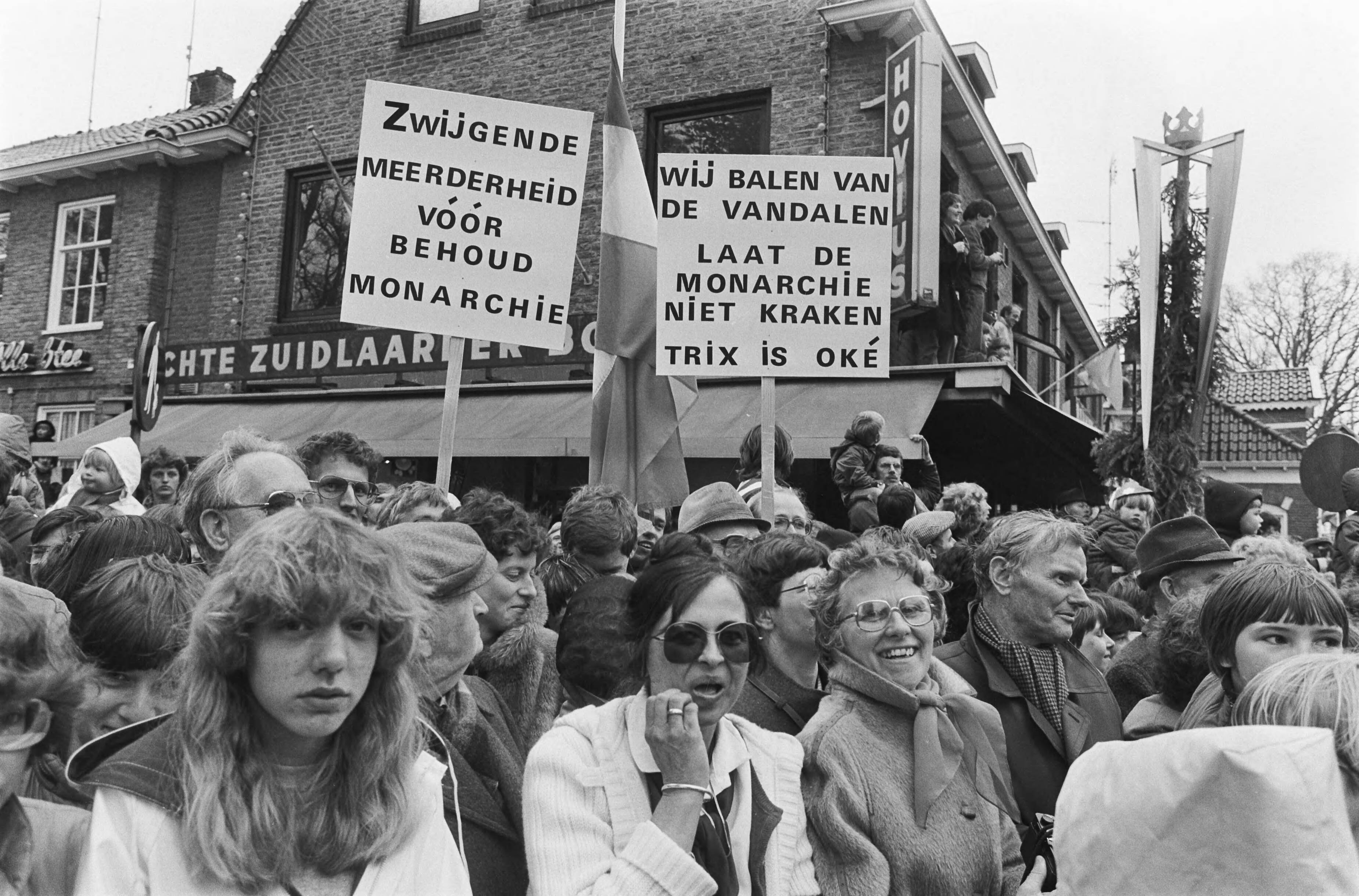 Fotocollectie Anefo — Koninginnedag, koninklijke familie in Zuidlaren. Twee borden voor behoud van monarchie en Beatrix — Foto: Bogaerts, Rob / Anefo. Licentie: Set B: Rechtenvrij / Publiek Domein. Bron: Nationaal Archief. http://hdl.handle.net/10648/ad1668c6-d0b4-102d-bcf8-003048976d84