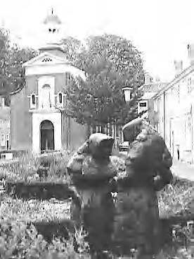 Fotocollectie Rijksvoorlichtingsdienst Eigen — Beeldengroep van twee begijntjes in de tuin van het Begijnhof te Breda met op de achtergrond de begijnhofkapel — Foto: Schuurman, Ralph L. / RVD. Licentie: Set B: Rechtenvrij / Publiek Domein. Bron: Nationaal Archief. http://hdl.handle.net/10648/af7329b0-d0b4-102d-bcf8-003048976d84
