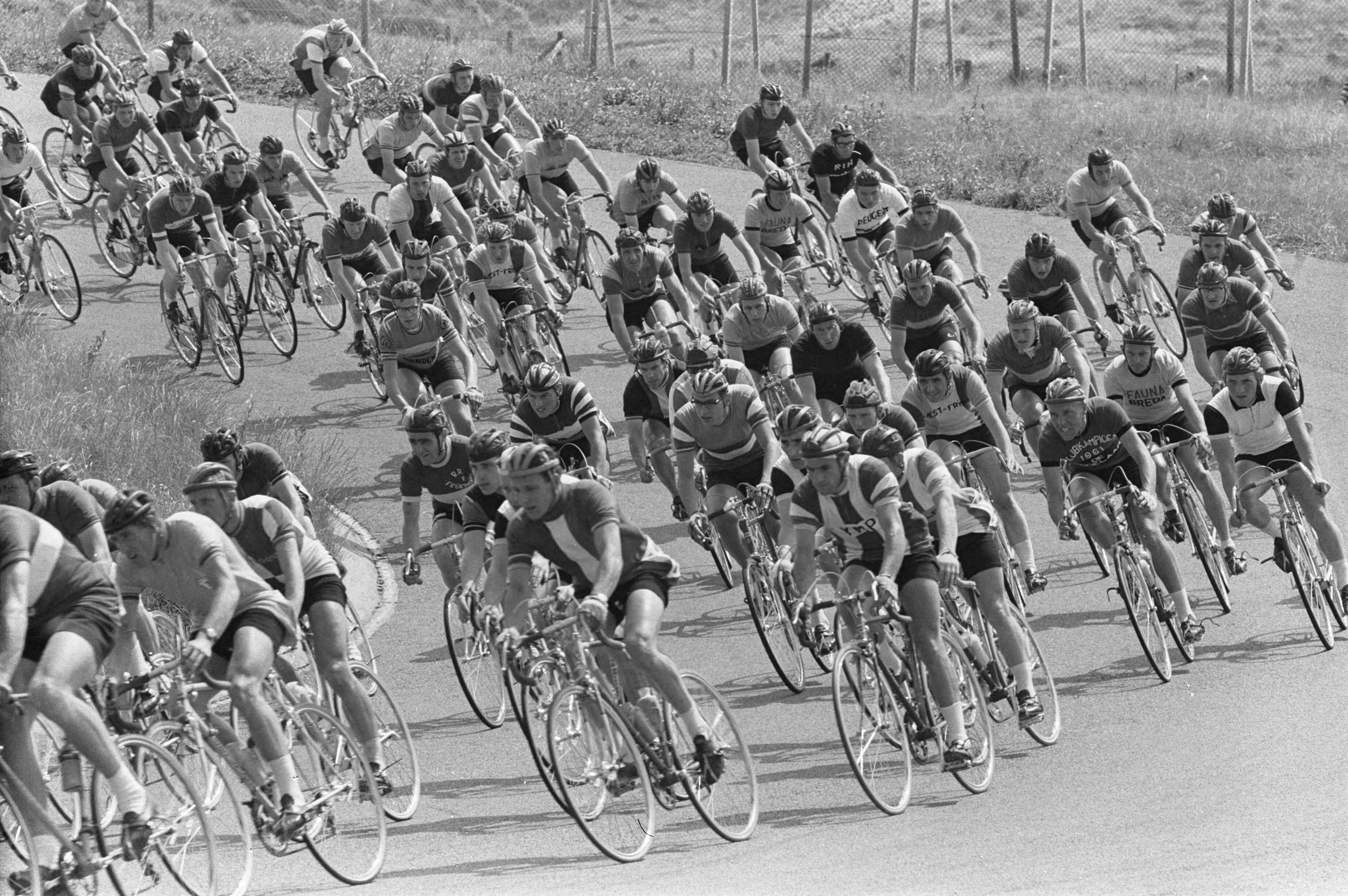 NK Wielrennen 1963 — Nederlands kampioenschap wielrennen op de weg op Circuit Zandvoort. Het enorme rennersveld in de bocht — Foto: Pot, Harry / Anefo. Licentie: Set B: Rechtenvrij / Publiek Domein. Bron: Nationaal Archief. http://hdl.handle.net/10648/aa3f3128-d0b4-102d-bcf8-003048976d84