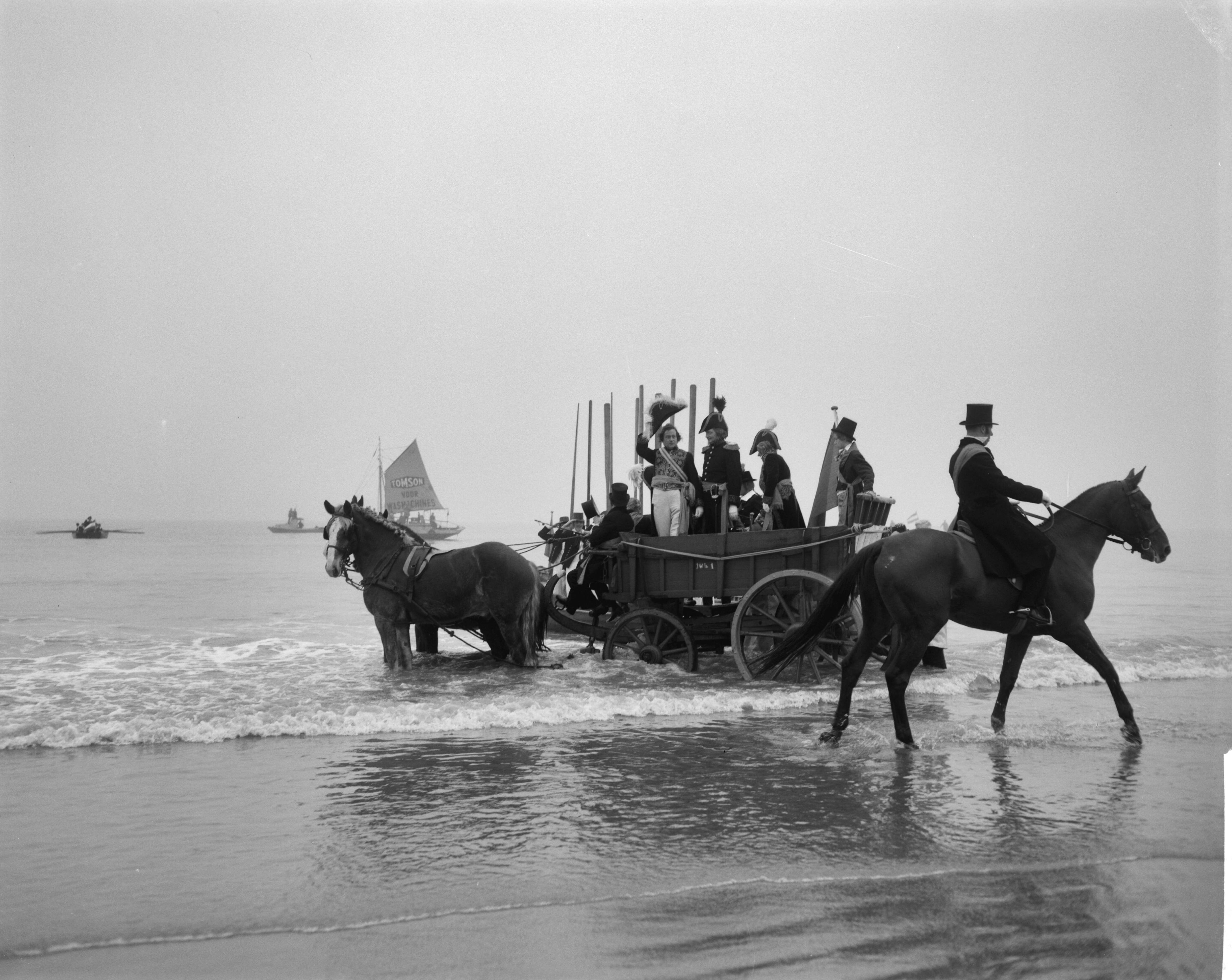 Fotocollectie Anefo — Te Scheveningen is de landing en intocht van prins Willem Frederik in 1813 herdacht. Aankomst van prins Willem Frederik op het strand. In een nettenwagen wordt hij van het strand gereden. In de voorgrond, met sjerp, het historisch personage Jacob Pronk — Foto: Bilsen, Joop van / Anefo. Licentie: Set B: Rechtenvrij / Publiek Domein. Bron: Nationaal Archief. http://hdl.handle.net/10648/aa501614-d0b4-102d-bcf8-003048976d84
