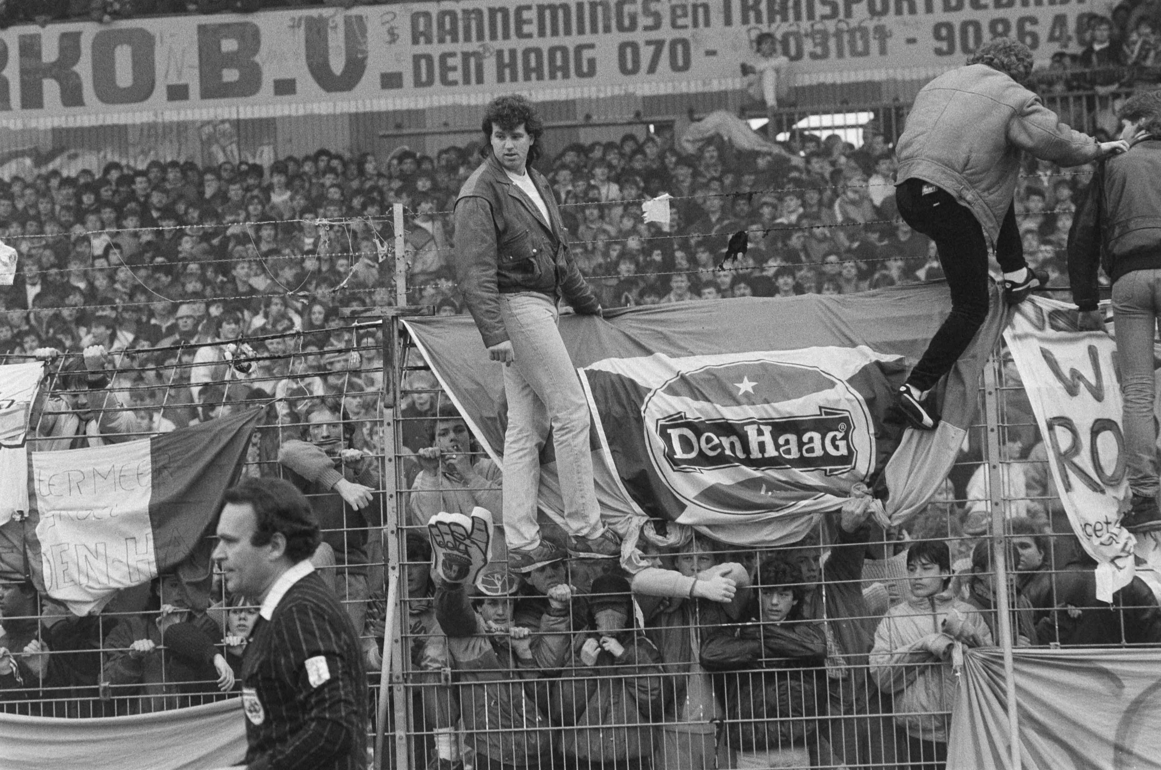Fotocollectie Anefo — Supportersrellen tijdens Den Haag tegen Ajax in Den Haag ; Den Haag supporters in actie — Foto: Molendijk, Bart / Anefo. Licentie: Set B: Rechtenvrij / Publiek Domein. Bron: Nationaal Archief. http://hdl.handle.net/10648/ad5d6032-d0b4-102d-bcf8-003048976d84