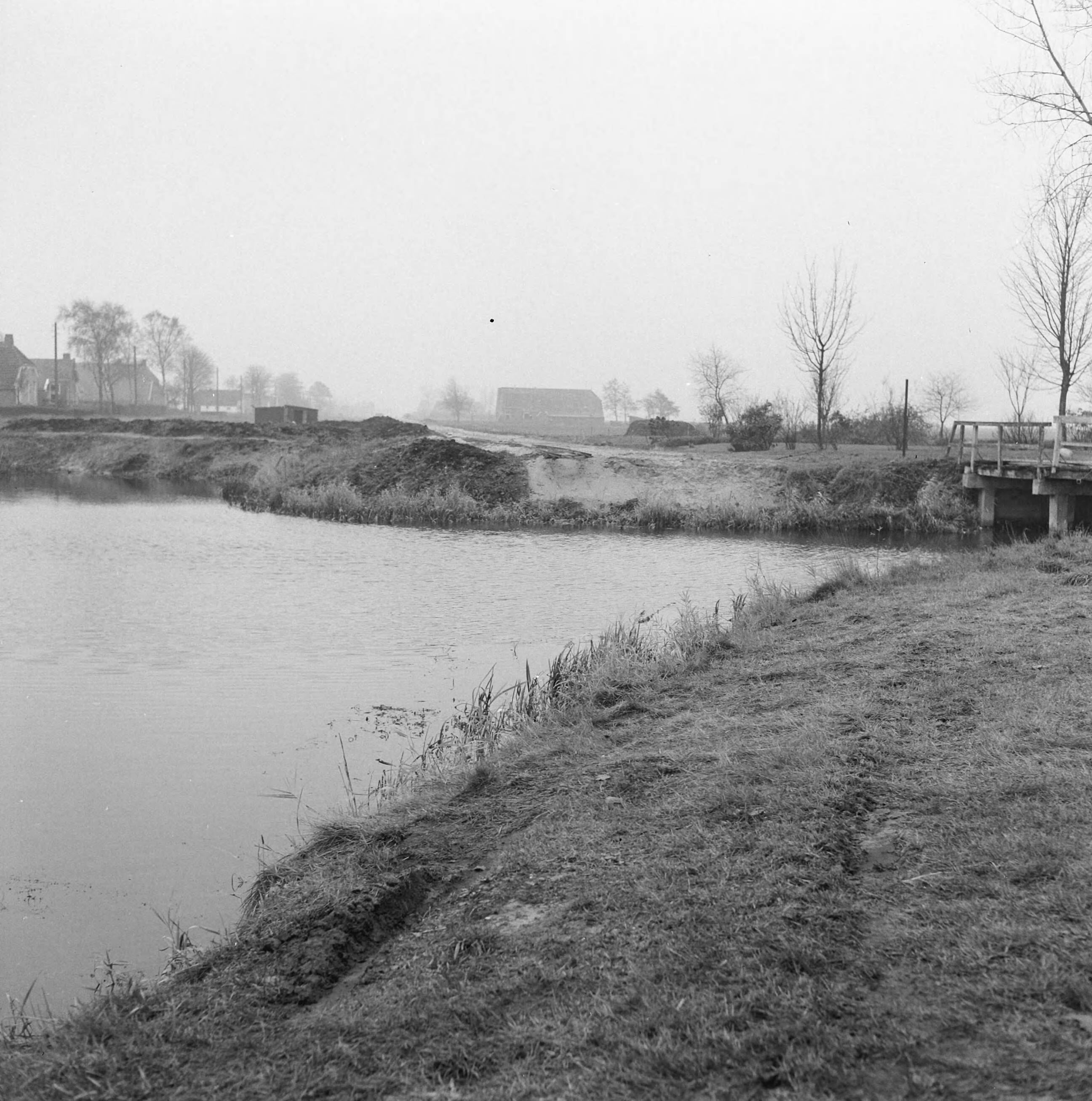 Fotocollectie Nederlandse Heidemaatschappij — Het dempen van het hoofdkanaal bijlangs de benendenste Veenweg. De bestaande sintelweg (links op de foto vlak voor de boerderijen langs) en het kanaal vervallen en wordt gespit tot bouwland. De nieuwe wegen komen grotendeels over de te dempen kanalen te lopen. Het zandkunst is hier te zien rechts van de houten schuilkeet. De brug recht overbrugt de zijwijkvan de fam. Maarsingh en Meursing. Deze wijk wordt afgesloten door de aanleg van de weg en daarna gedempt — Foto: Wüllschleger, [...] / Heidemij. Licentie: Set B: Rechtenvrij / Publiek Domein. Bron: Nationaal Archief. http://hdl.handle.net/10648/ae71c800-d0b4-102d-bcf8-003048976d84