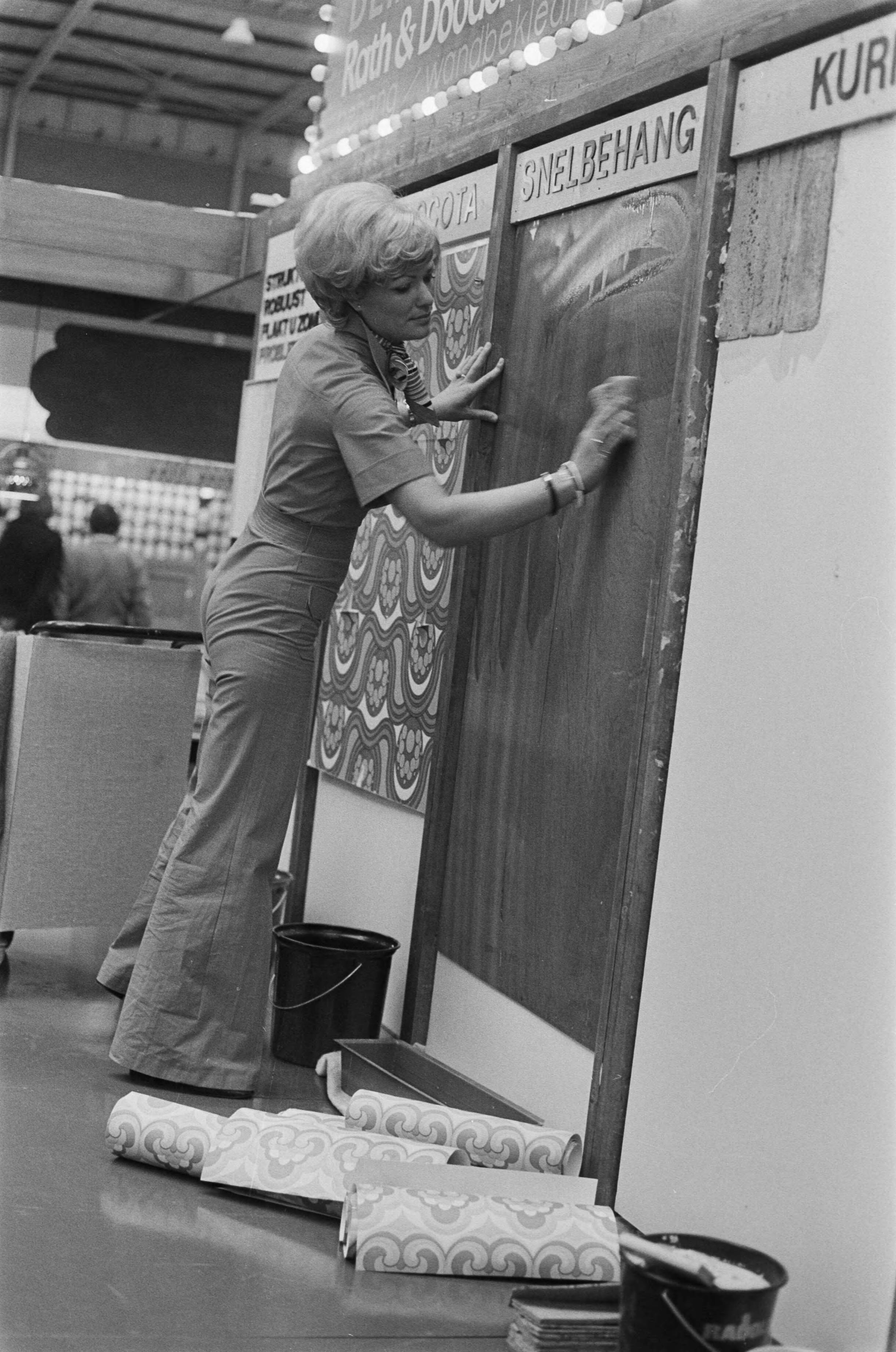 Fotocollectie Anefo — Beurs: Karwei "76 in Utrechtse Jaarbeurs; dame demonstreert snelbehang — Foto: Bogaerts, Rob / Anefo. Licentie: Set B: Rechtenvrij / Publiek Domein. Bron: Nationaal Archief. http://hdl.handle.net/10648/ac7bc528-d0b4-102d-bcf8-003048976d84