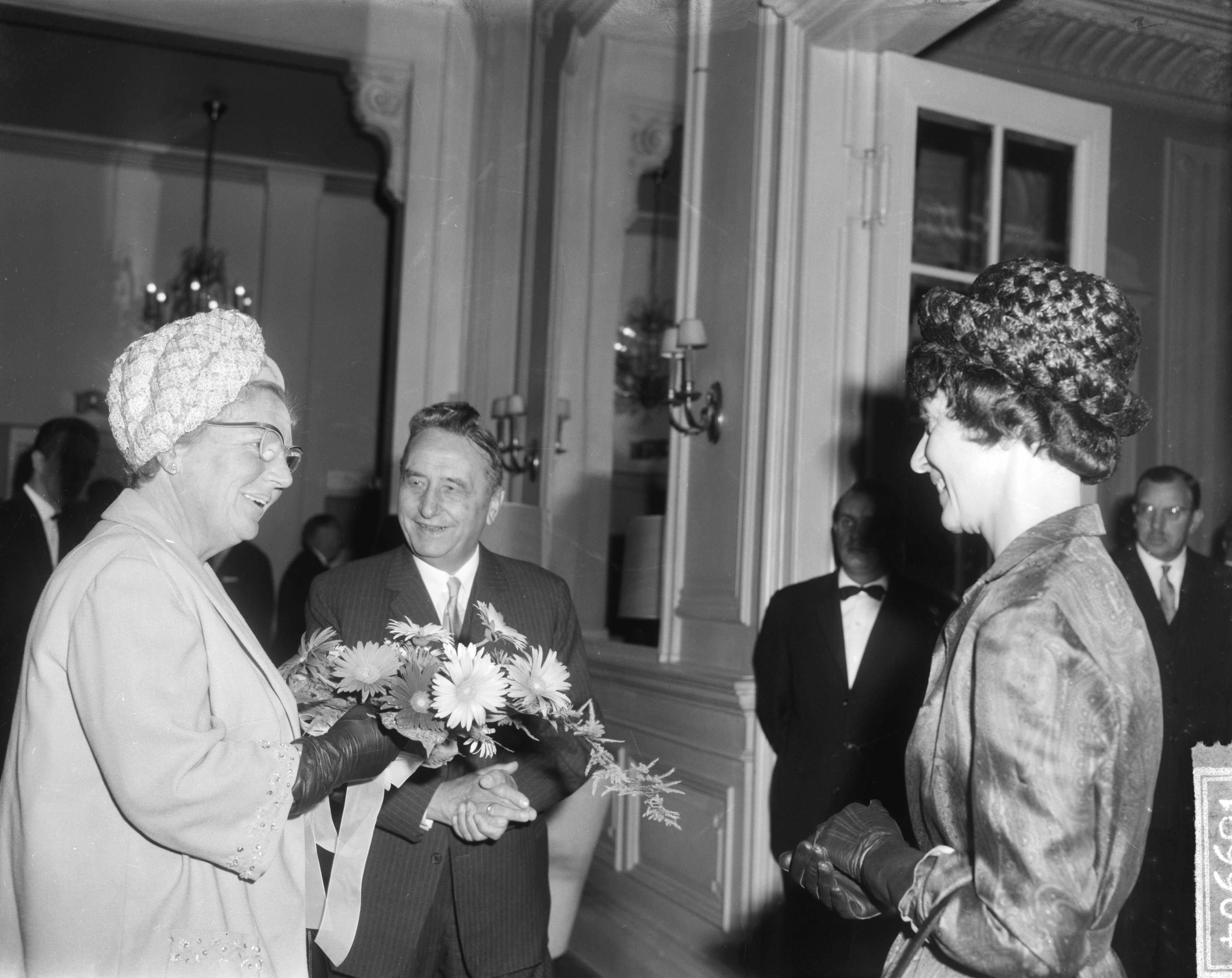 Koningin Juliana woont in het Kurhaus in Scheveningen het congres van het Genootschap "Onze Taal" bij — Koningin Juliana woont in het Kurhaus in Scheveningen het congres van het Genootschap "Onze Taal" bij. Mevrouw Th. Veering-Feigl geeft koningin Juliana bloemen — Foto: Bilsen, Joop van / Anefo. Licentie: Set B: Rechtenvrij / Publiek Domein. Bron: Nationaal Archief. http://hdl.handle.net/10648/aa7d8d88-d0b4-102d-bcf8-003048976d84