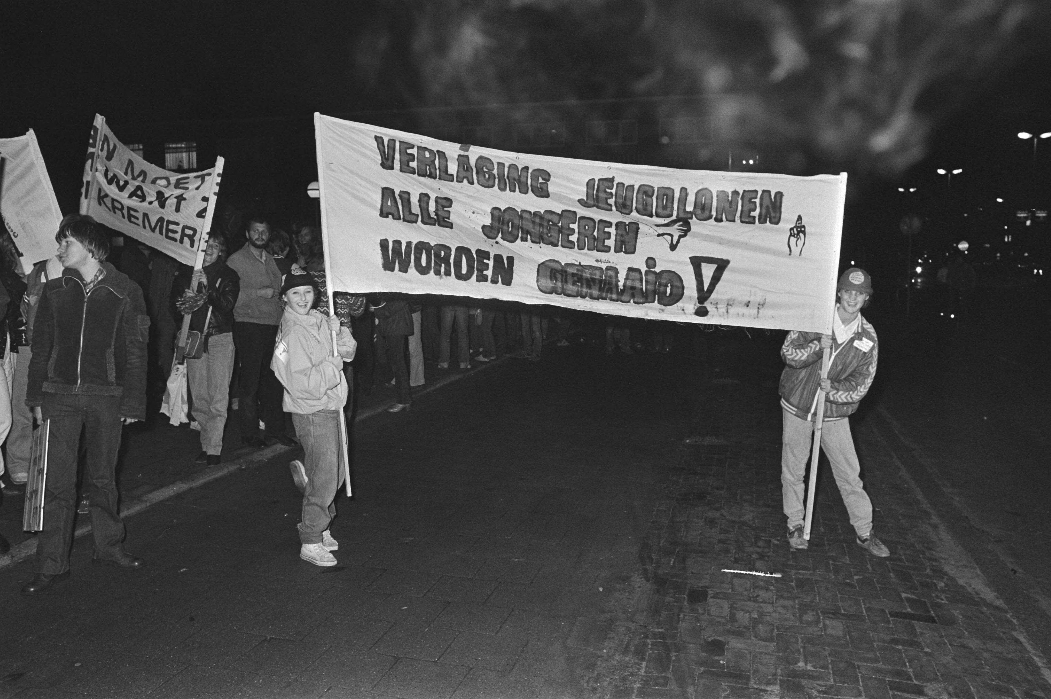 Fotocollectie Anefo — In Utrecht dem. vananvond jongeren-organisaties tegen voornemens regering jeugdlonen verlaging, ook militairen liepen mee (wedde-verlaging) — Foto: Bogaerts, Rob / Anefo. Licentie: Set B: Rechtenvrij / Publiek Domein. Bron: Nationaal Archief. http://hdl.handle.net/10648/acec3380-d0b4-102d-bcf8-003048976d84